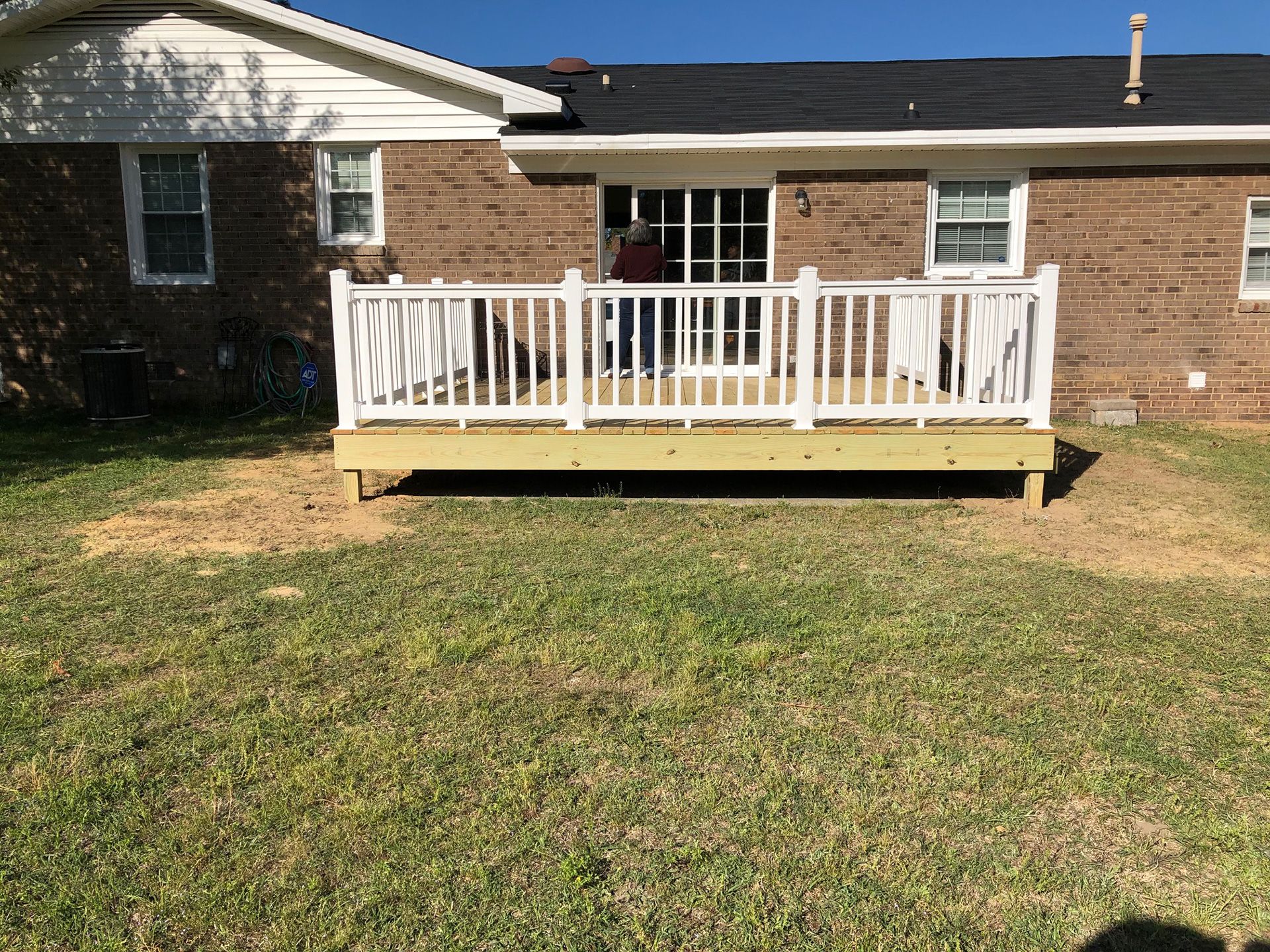 low deck on back of brick house with white railings