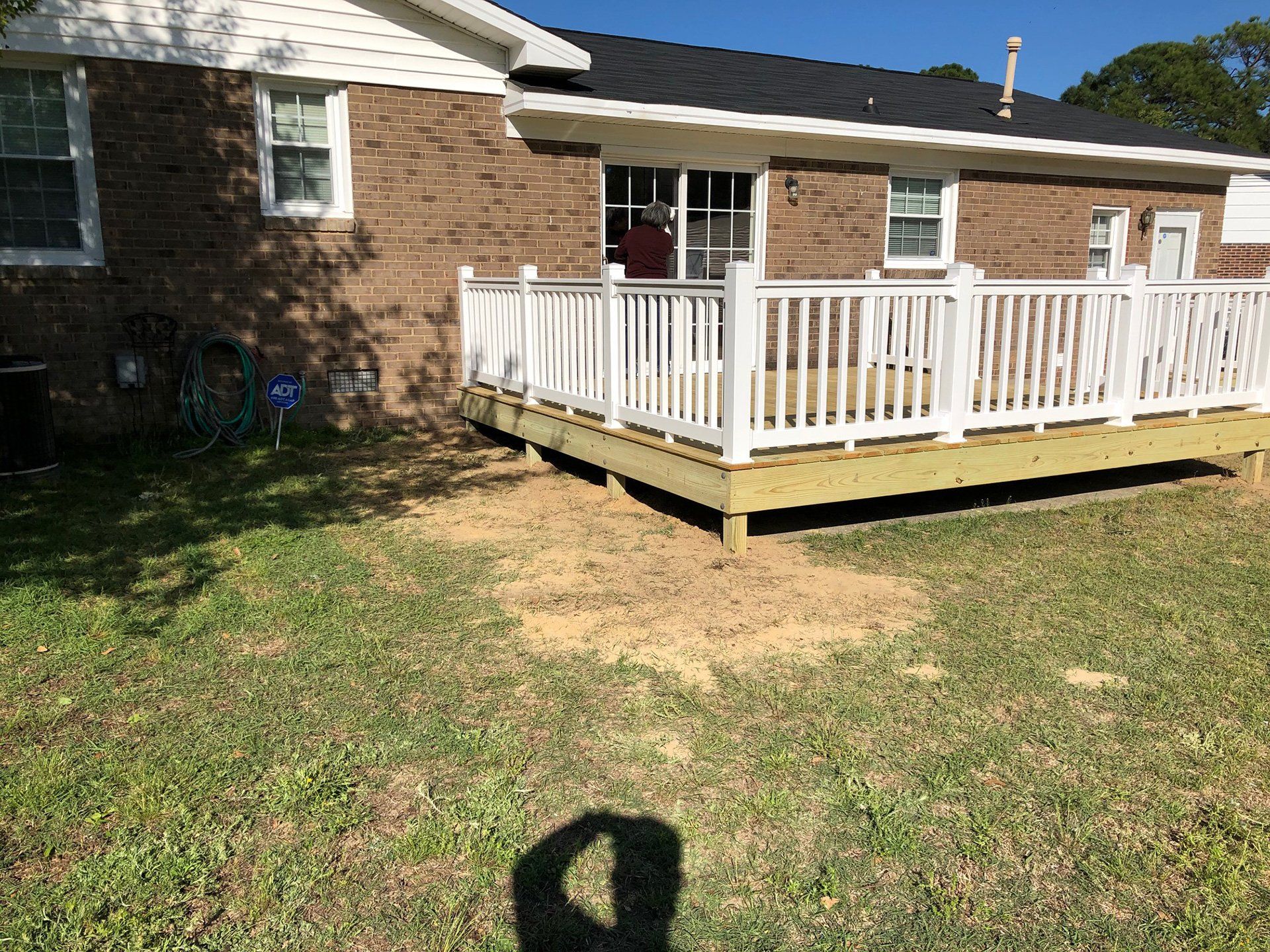low deck on back of brick house with white railings