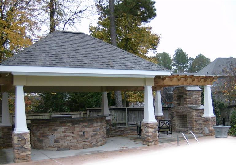 covered outdoor kitchen with pergola structure attached on one side with fireplace
