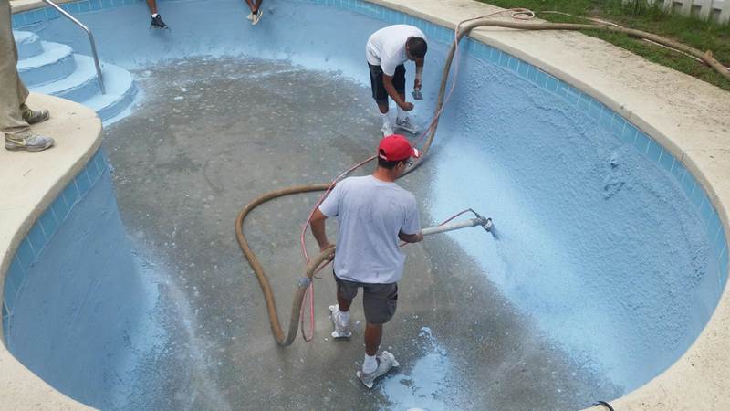 workers spraying replaster in pool