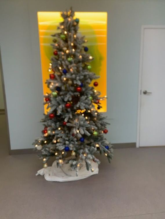 A christmas tree is sitting in a room next to a window.