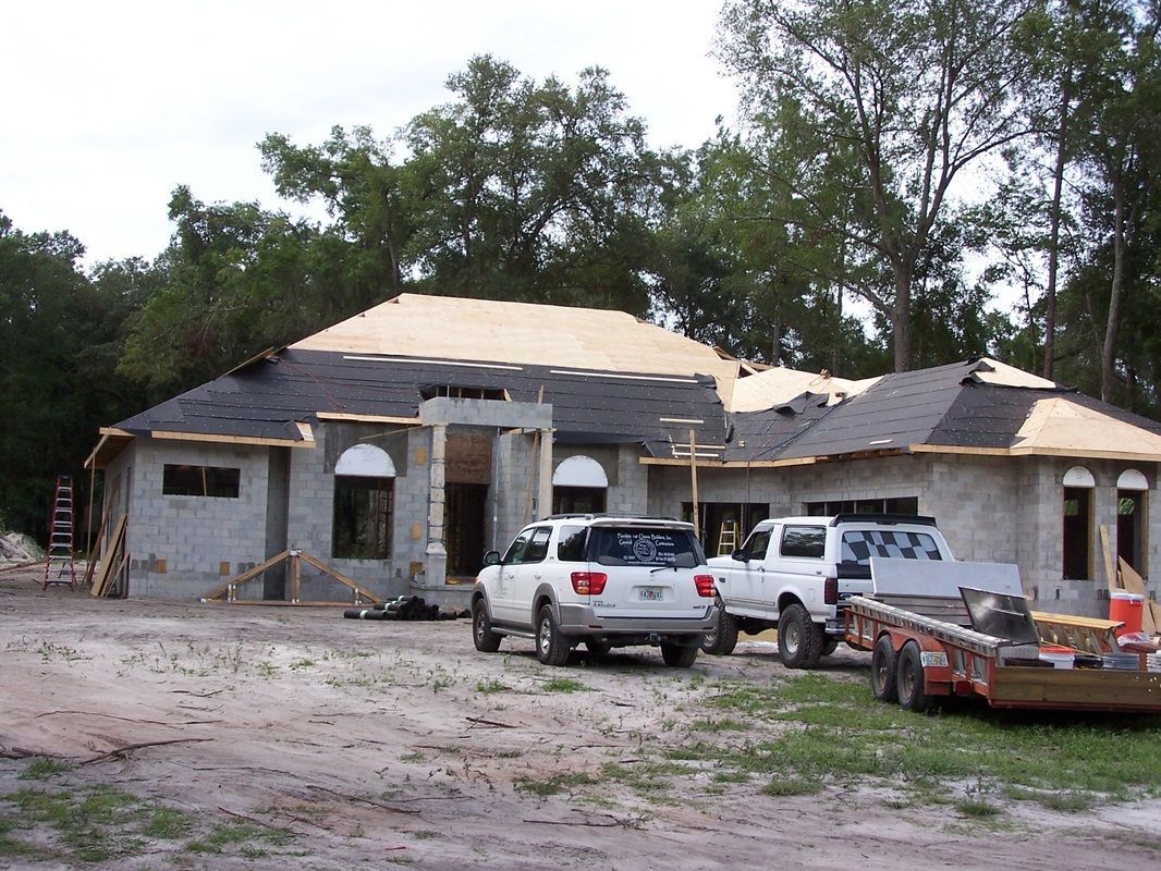 A house under construction with cars parked in front of it