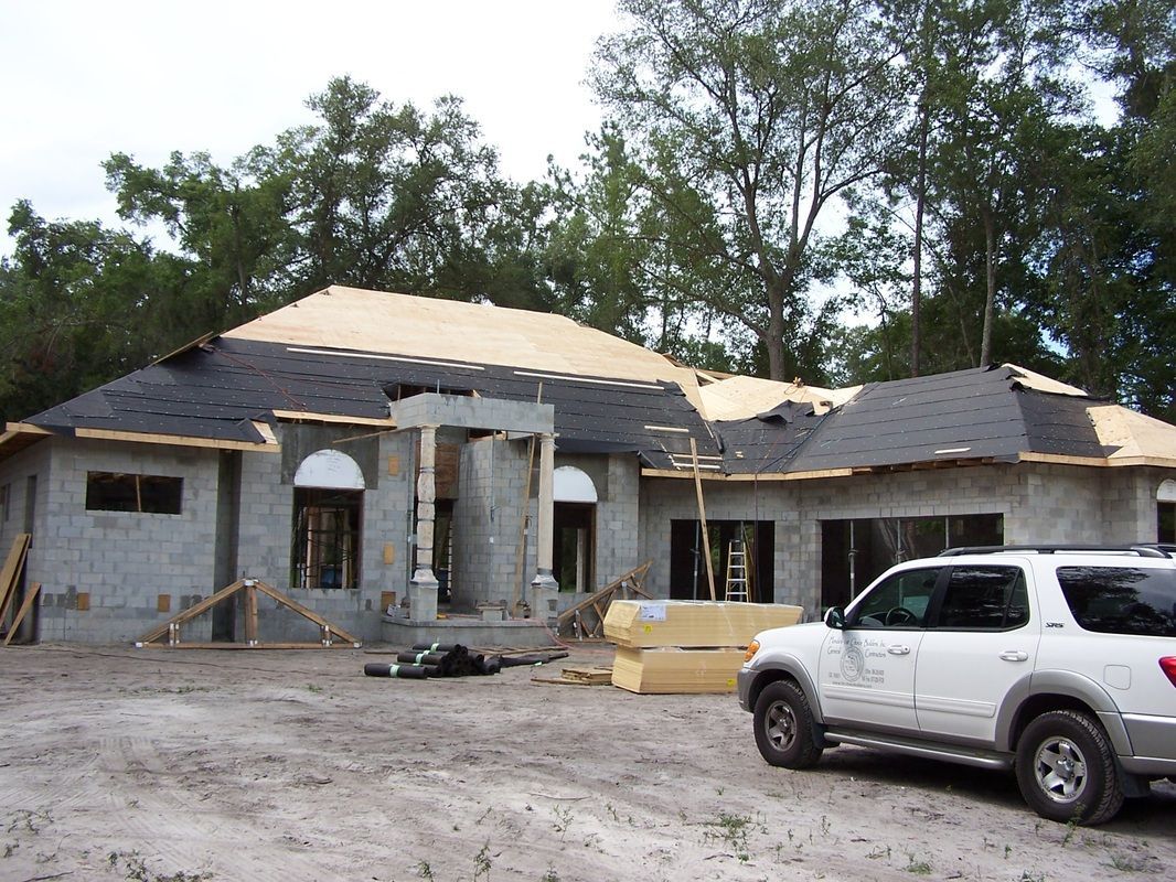 A white suv is parked in front of a house under construction