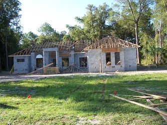 A house is being built in the middle of a lush green field.