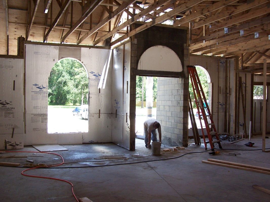 A man is working on a wall in a building under construction