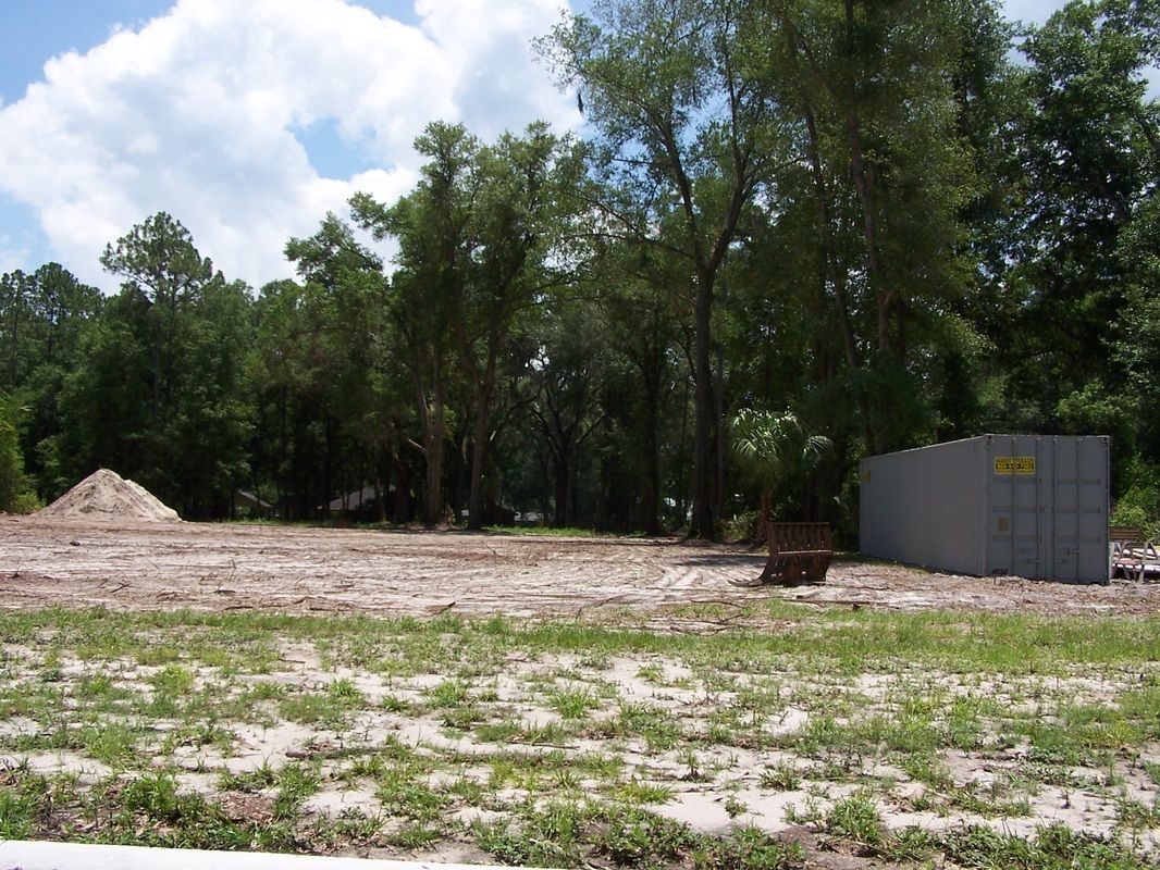 A large concrete container is in the middle of a grassy field surrounded by trees.