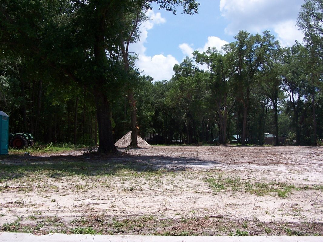 A dirt field with trees in the background