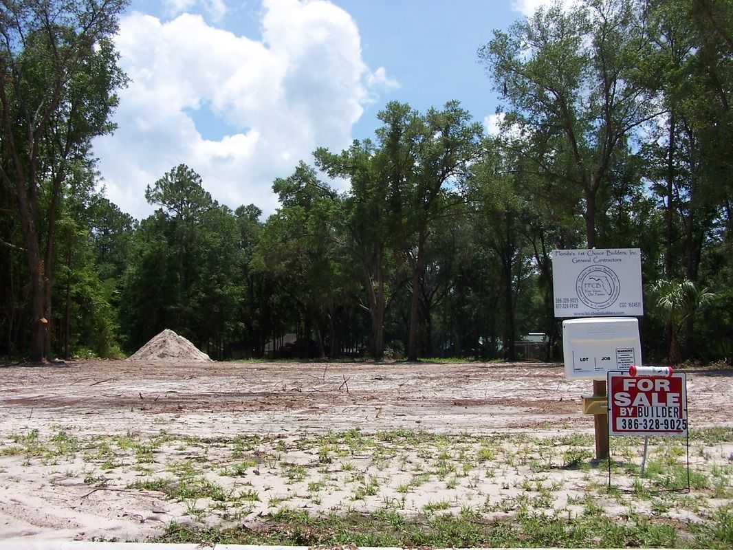 A for sale sign is in the middle of a dirt field
