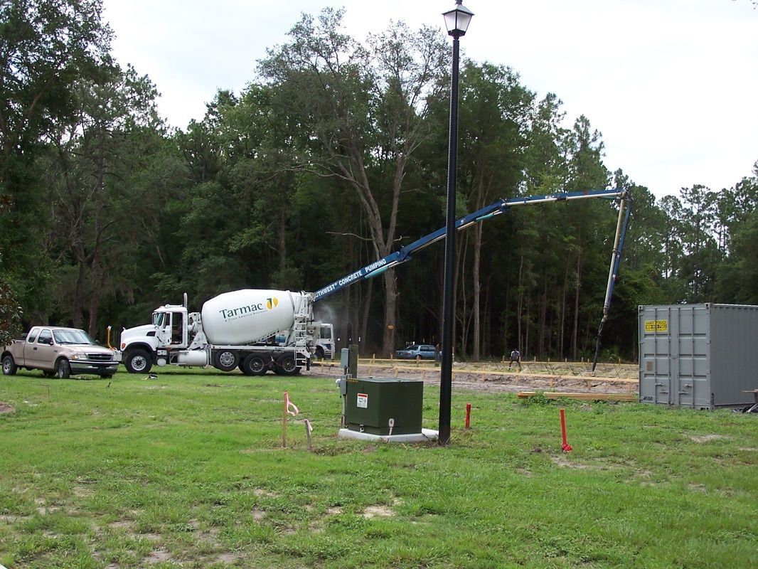A concrete mixer truck is driving through a grassy field