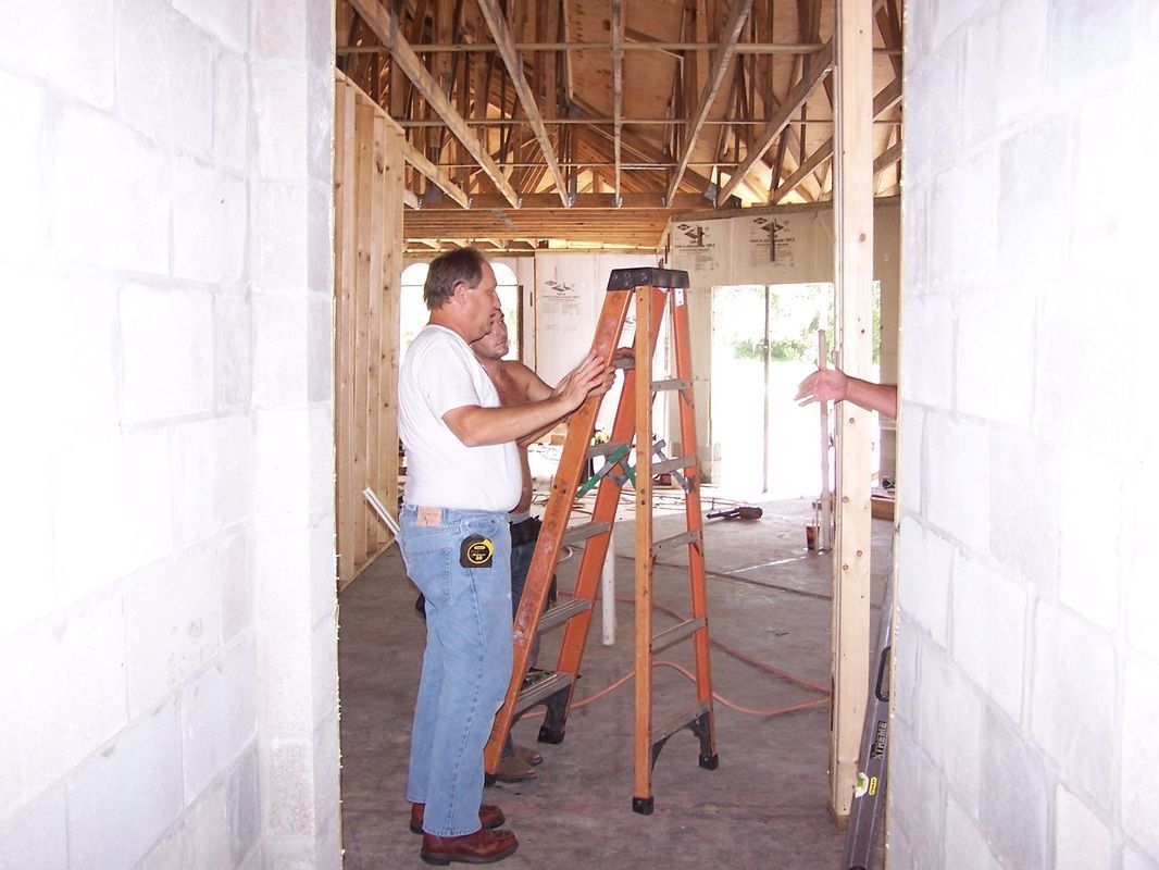 Two men are standing next to a ladder in a building under construction.