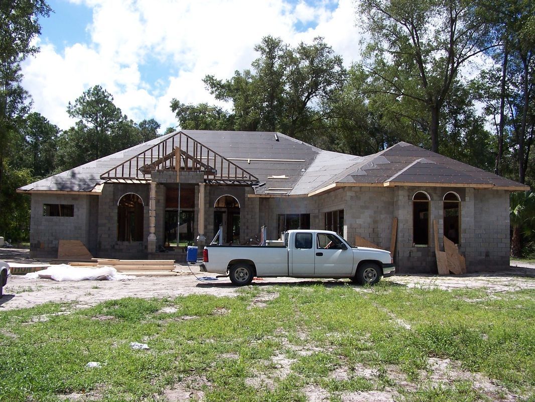 A white truck is parked in front of a house under construction