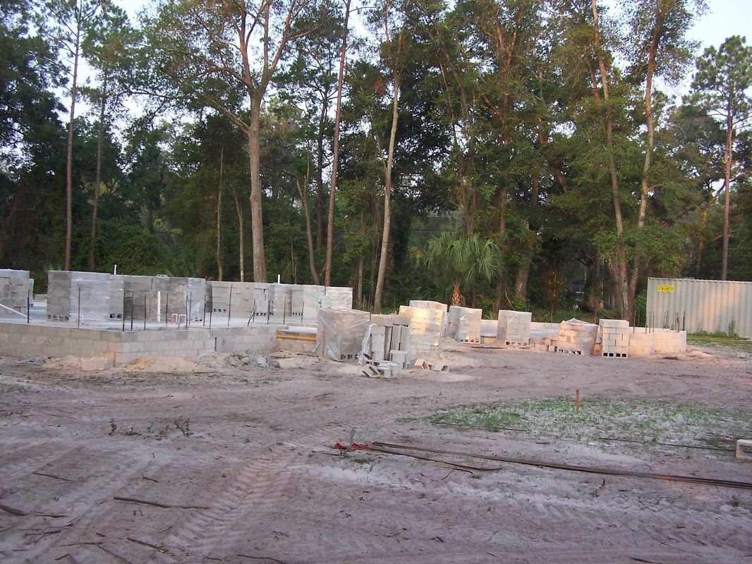 A row of concrete blocks in a dirt field with trees in the background