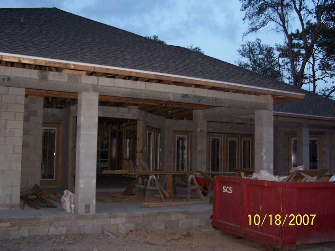 A red dumpster sits in front of a house under construction