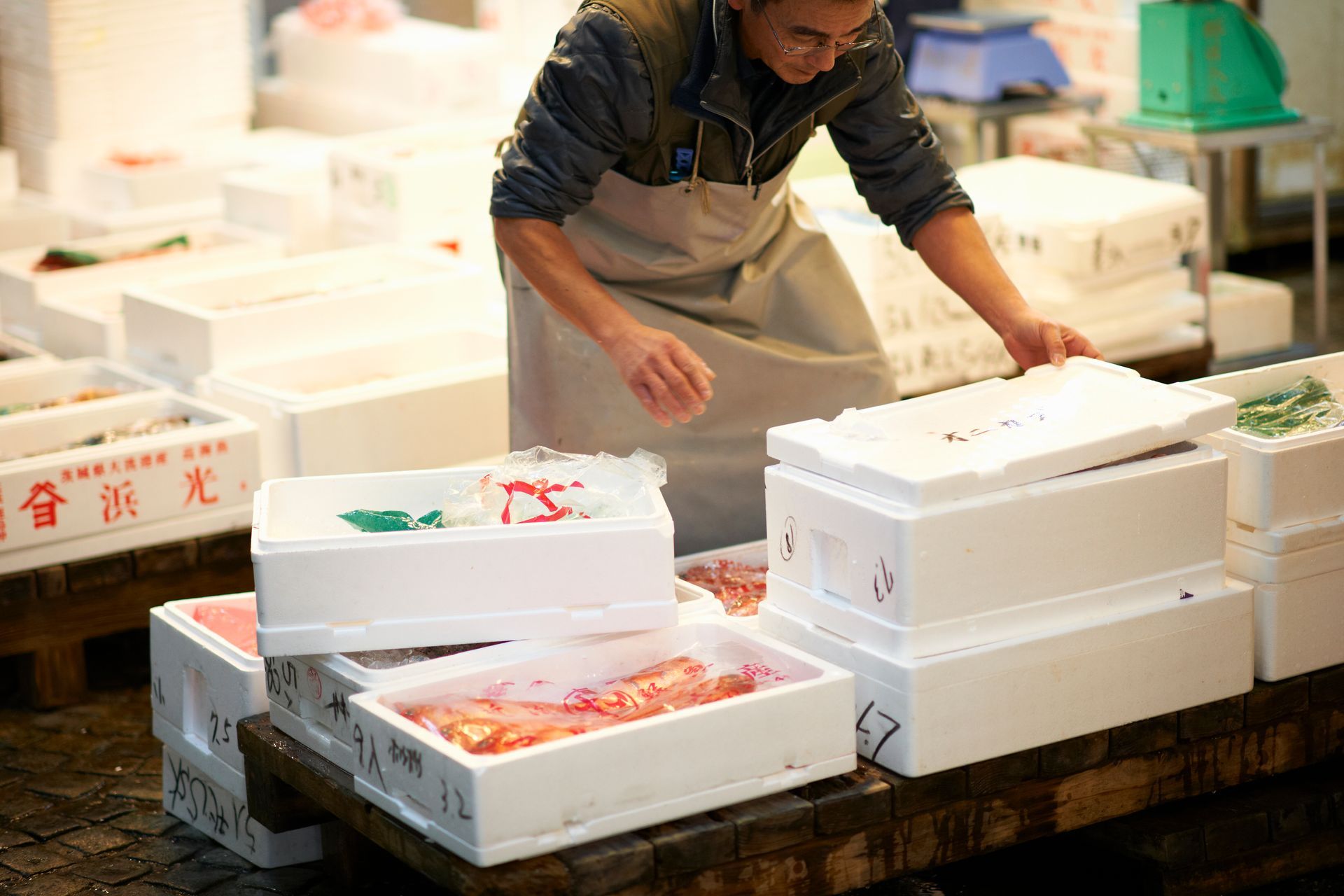 Market worker organizing fresh seafood at dawn.