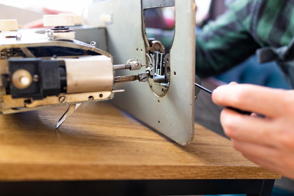 A Person is Fixing a Sewing Machine With a Screwdriver — James Hunter Mobile Sewing Machine Mechanic in Maroochydore, QLD