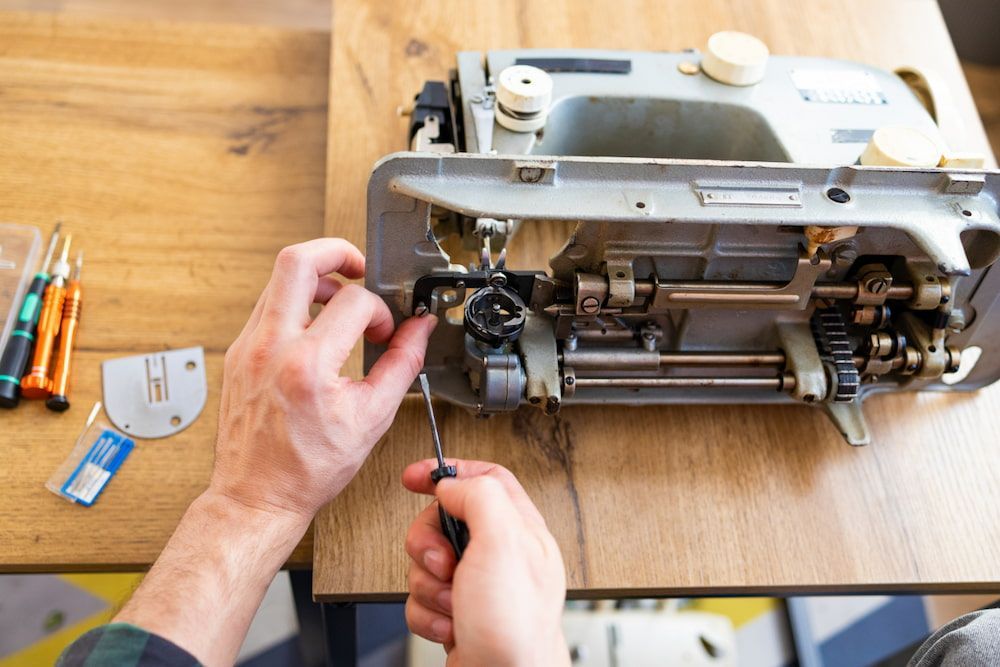 A Person is Fixing a Sewing Machine on a Wooden Table — James Hunter Mobile Sewing Machine Mechanic in Battery Hill, QLD