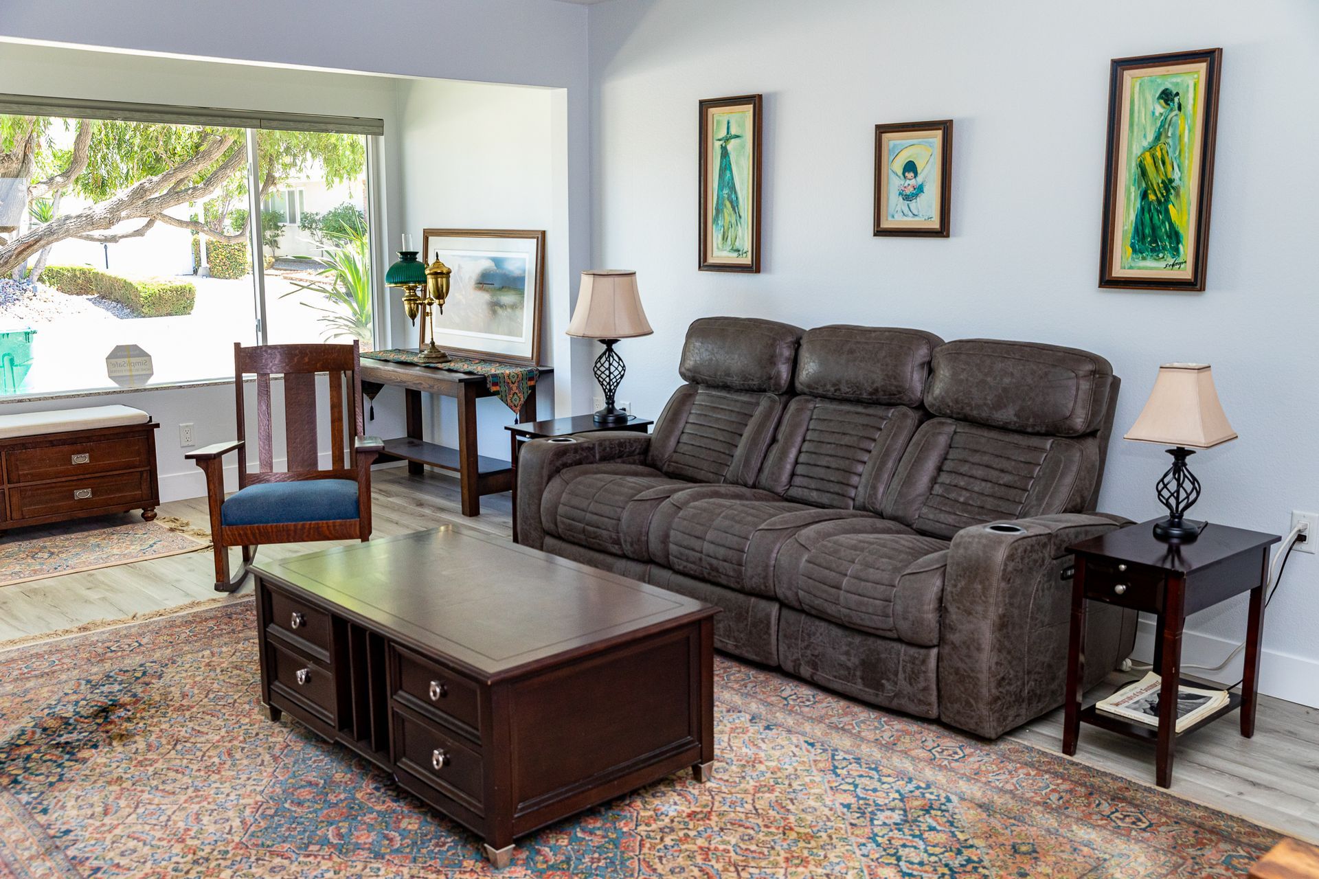 A living room with a couch , chair , coffee table and lamps.