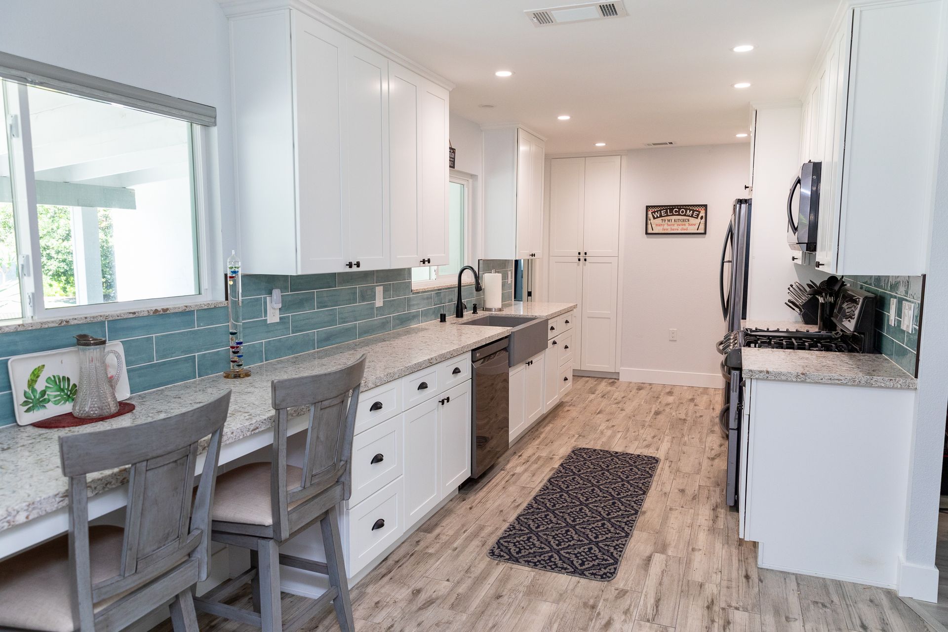 A kitchen with white cabinets , granite counter tops , and stainless steel appliances.