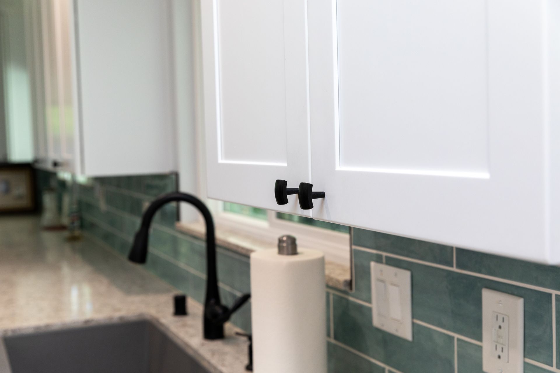 A kitchen sink with a paper towel holder and a black faucet.