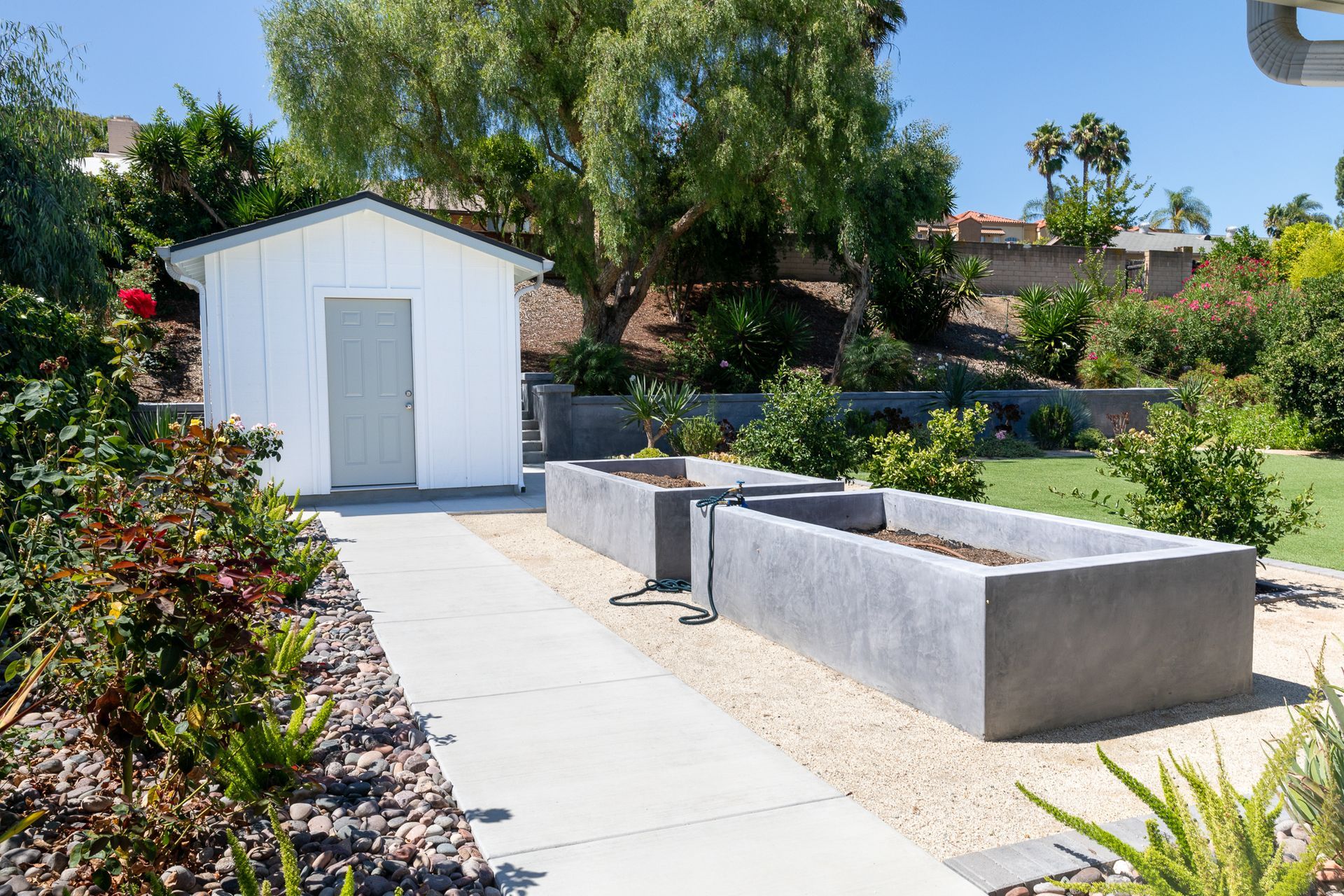 A white shed is sitting in the middle of a garden.