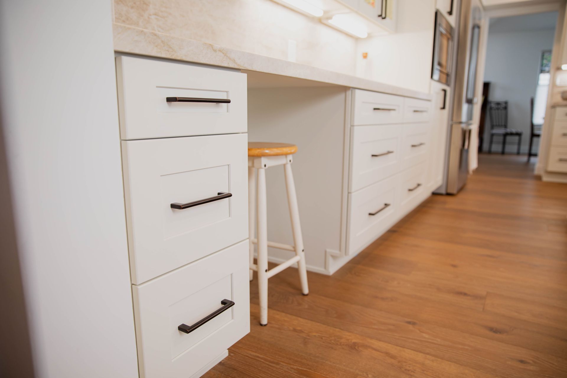 A kitchen with white cabinets and a wooden stool.
