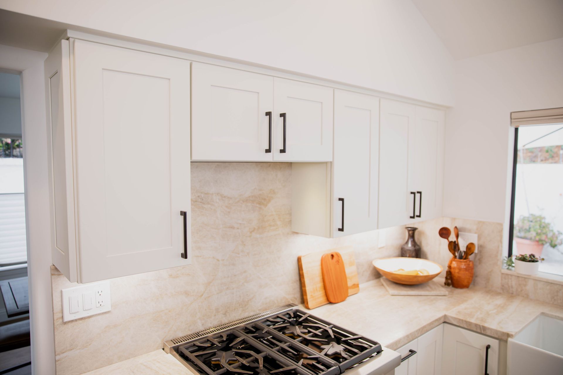 A kitchen with white cabinets and a stove top oven.
