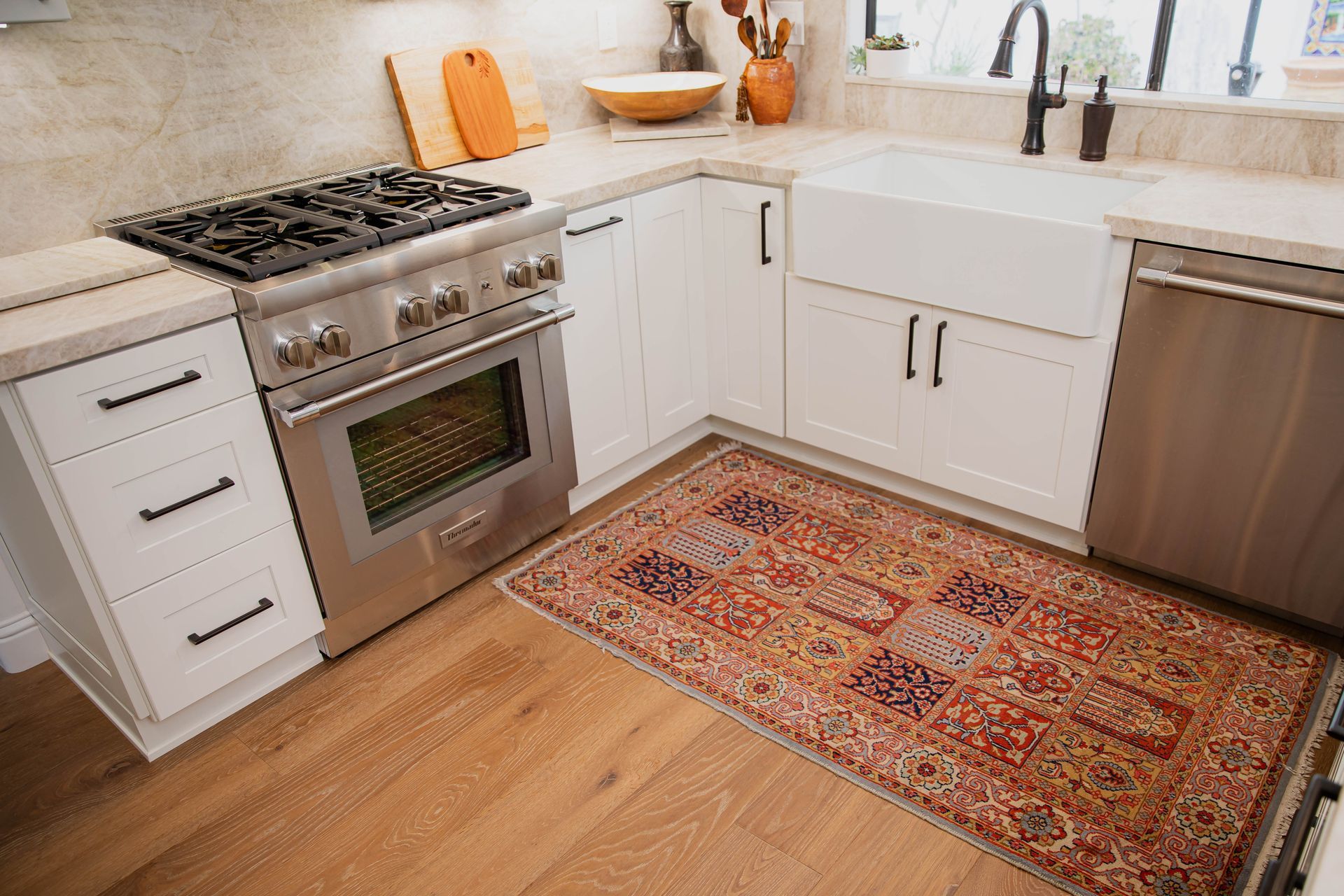 A kitchen with a rug on the floor and a stove.