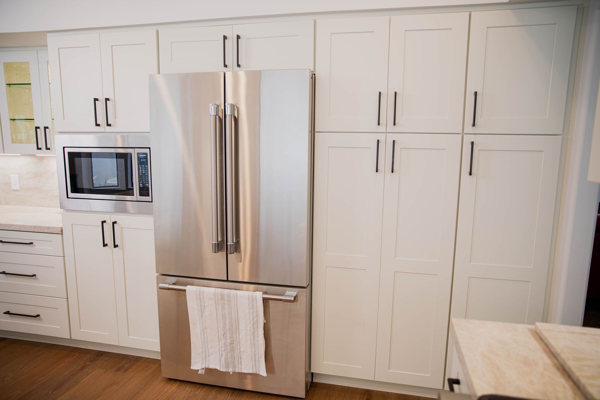 A kitchen with white cabinets and a stainless steel refrigerator.