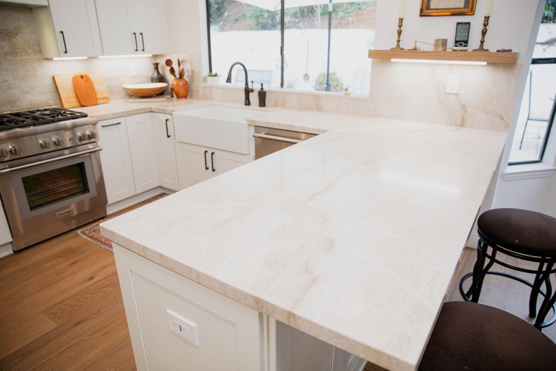A kitchen with white cabinets , a stove , a sink , and a large island.