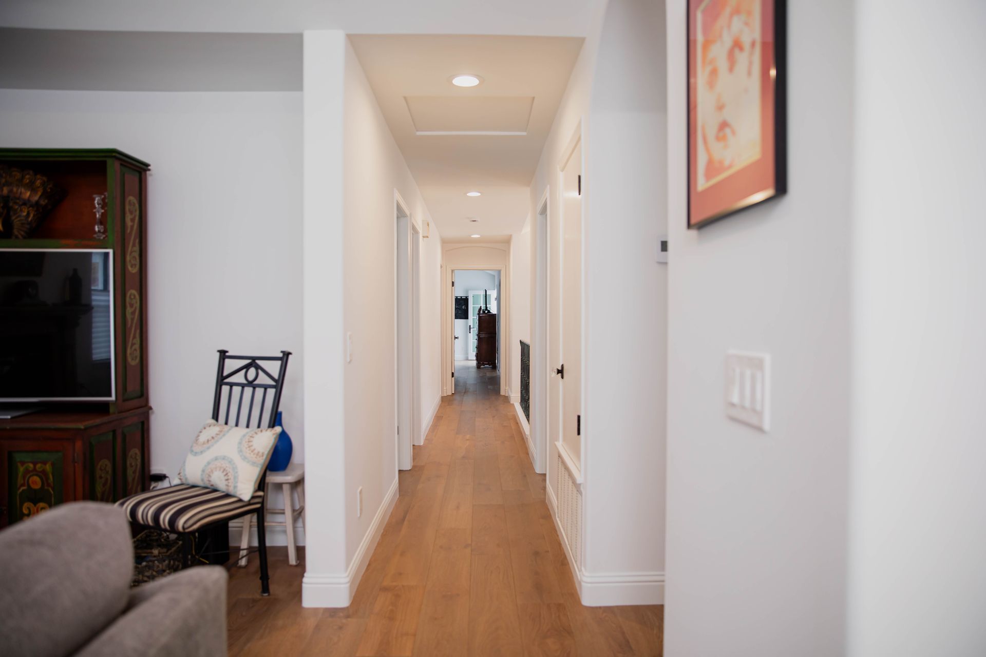 A long hallway in a house with hardwood floors and white walls.