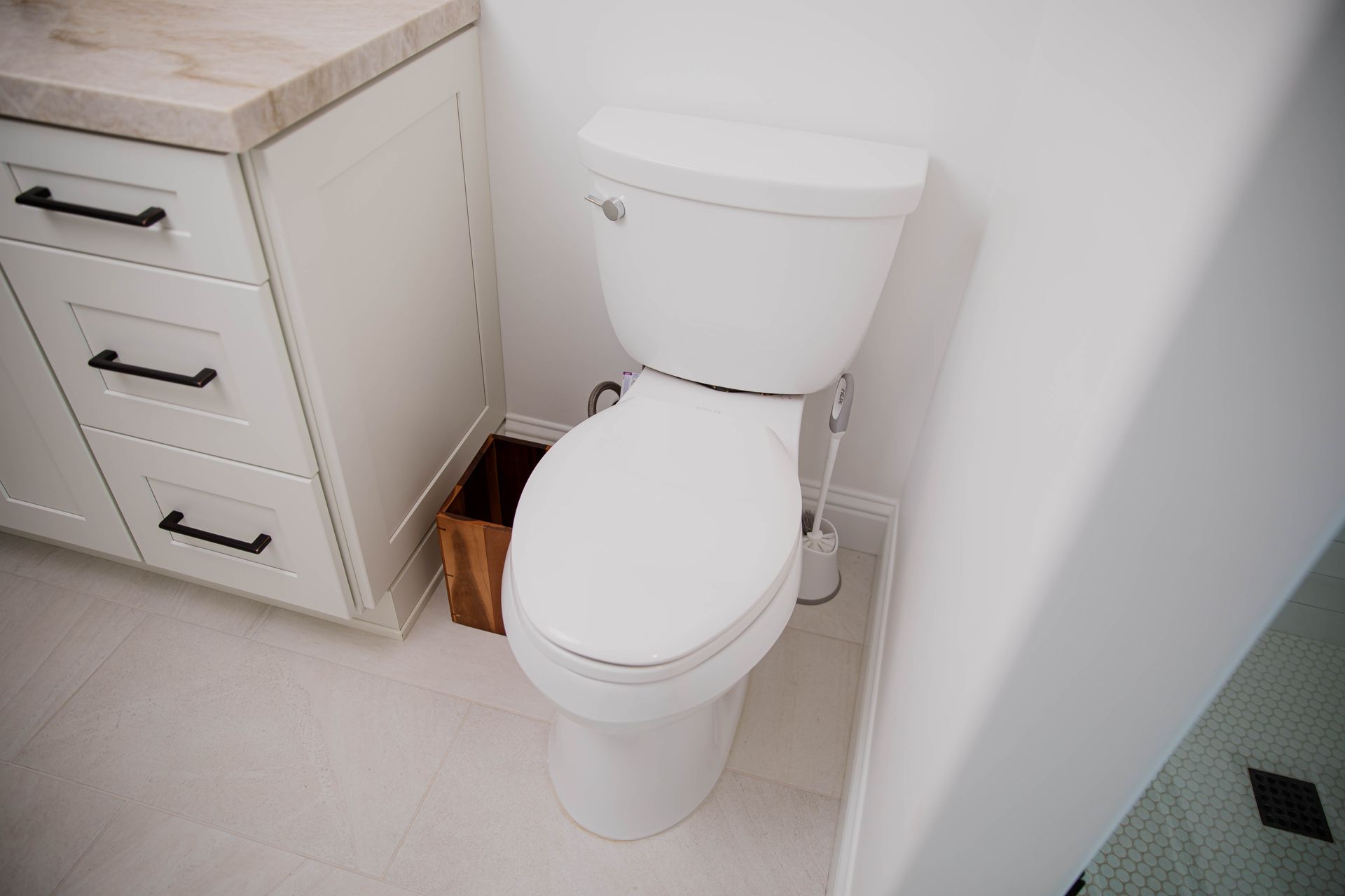 A white toilet is sitting in a bathroom next to a trash can.