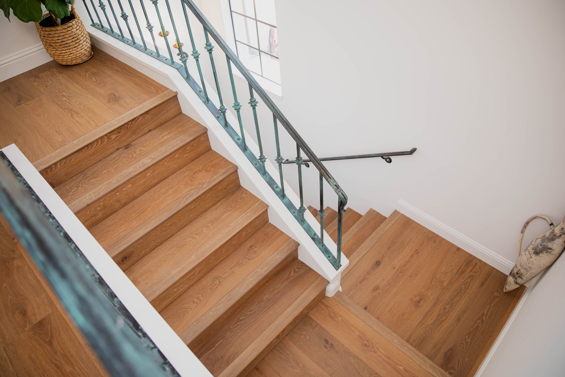 A wooden staircase with a wrought iron railing and a plant in the background.