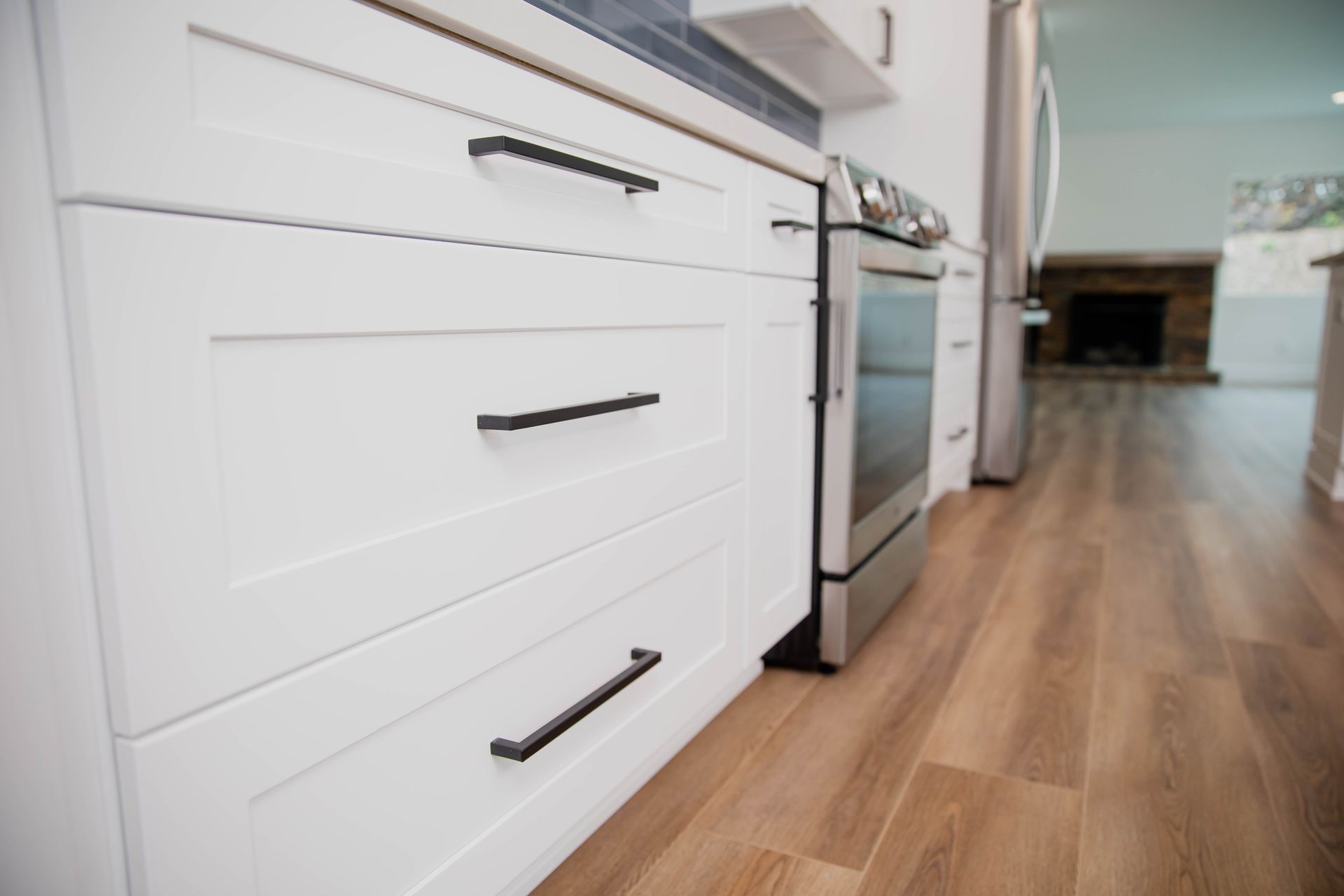 A kitchen with white cabinets and black handles and a stove.