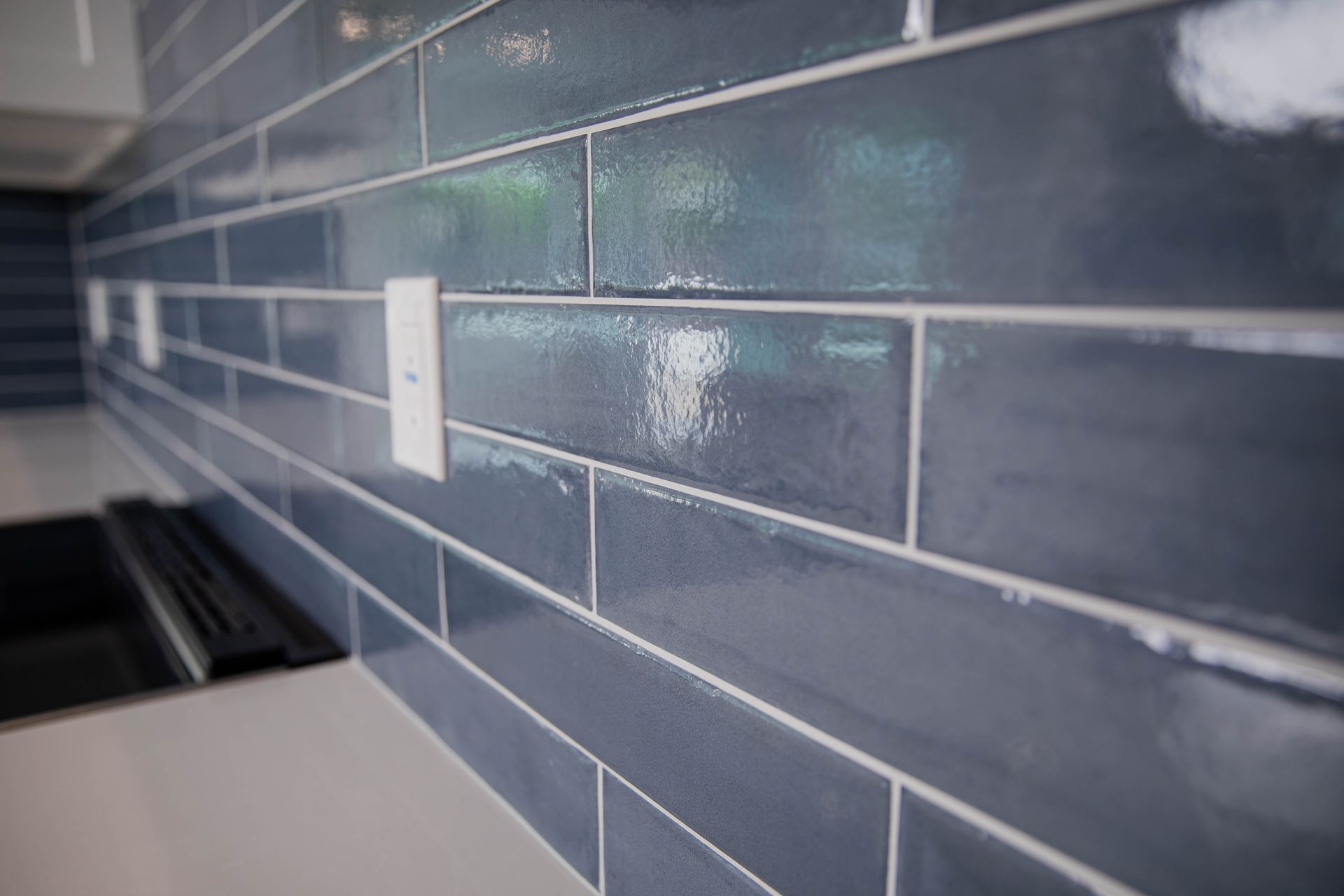 A kitchen with blue tiles and a white counter top.