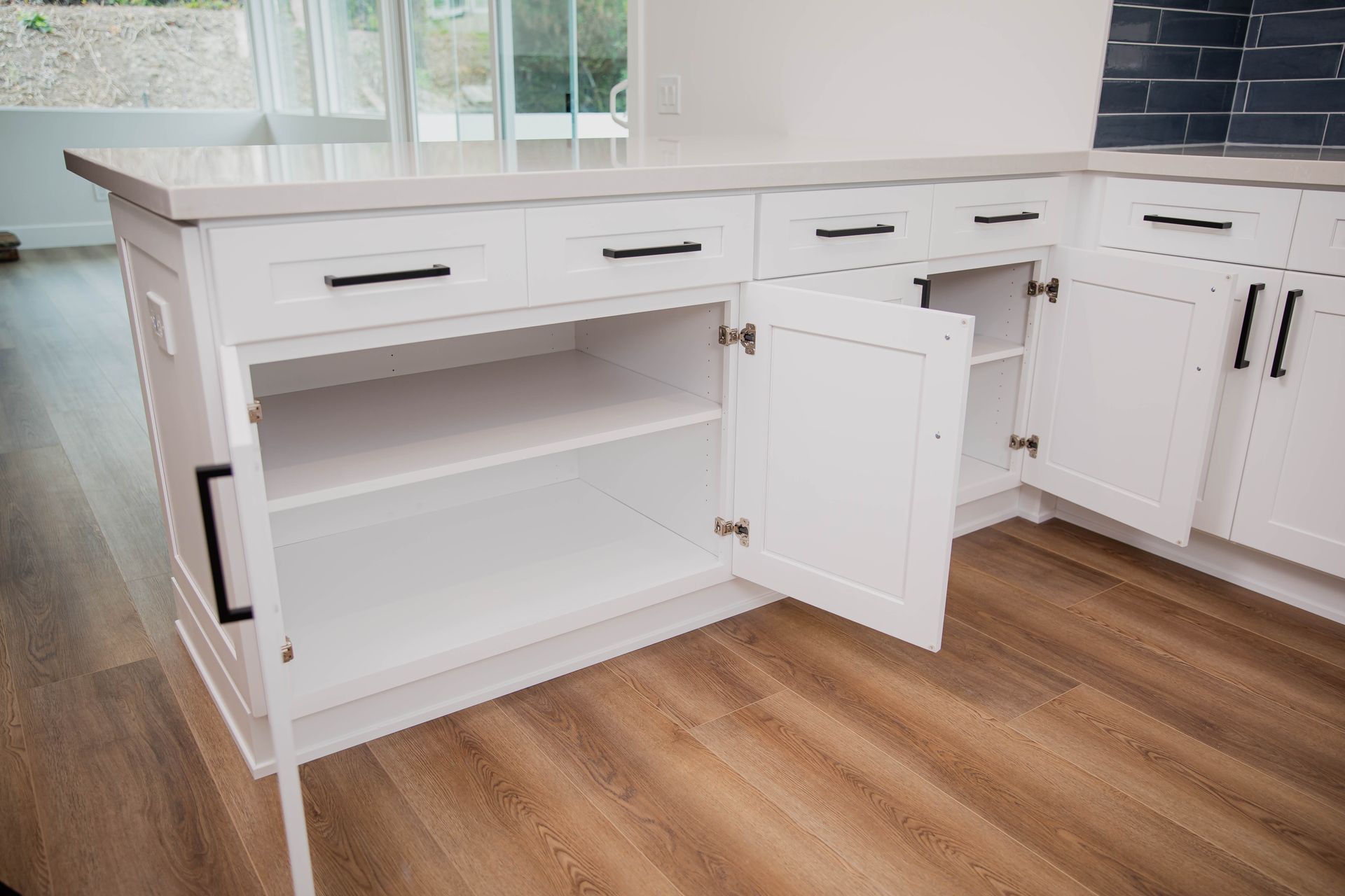 A kitchen with white cabinets and drawers with the doors open.