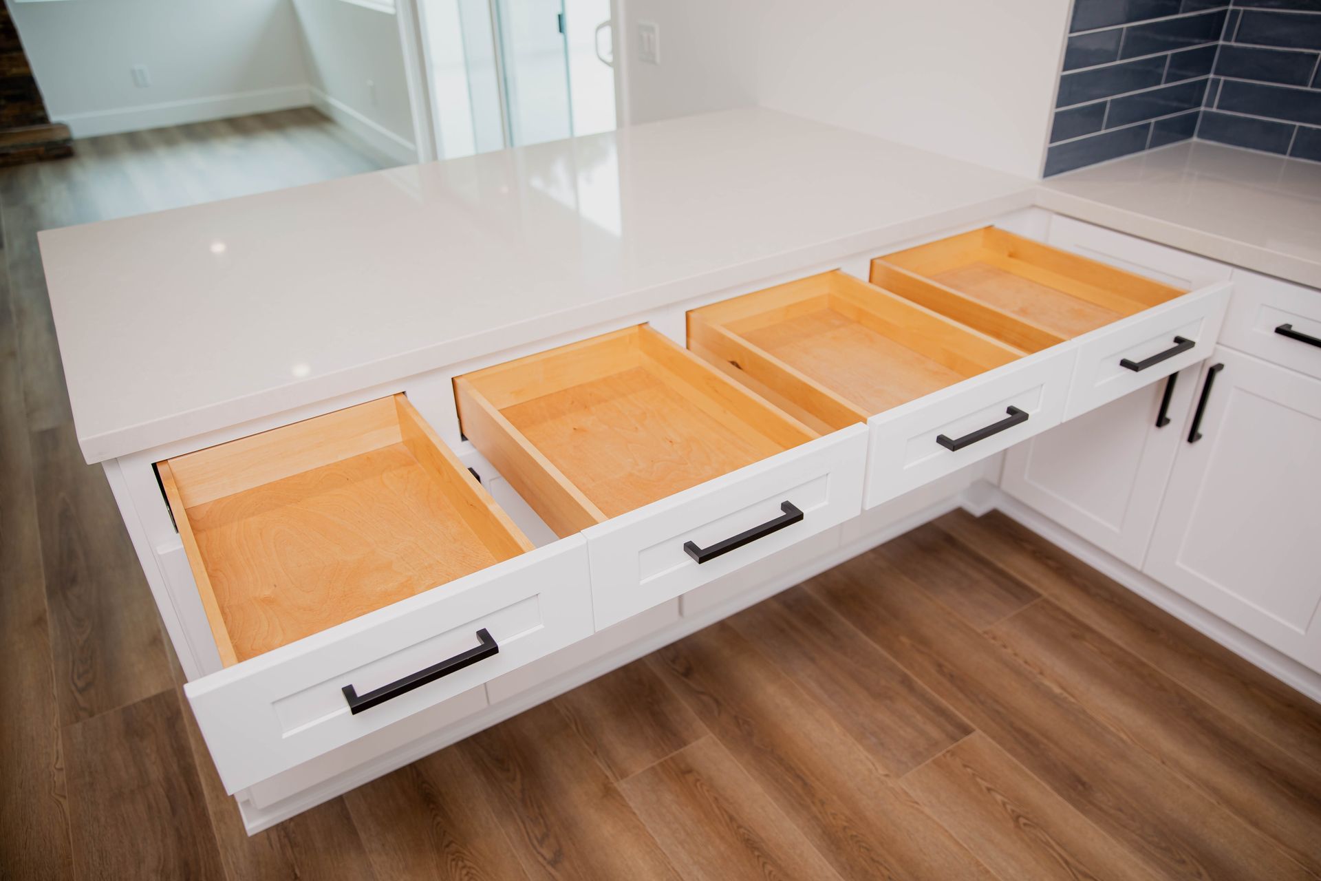 A kitchen with white cabinets and wooden drawers.