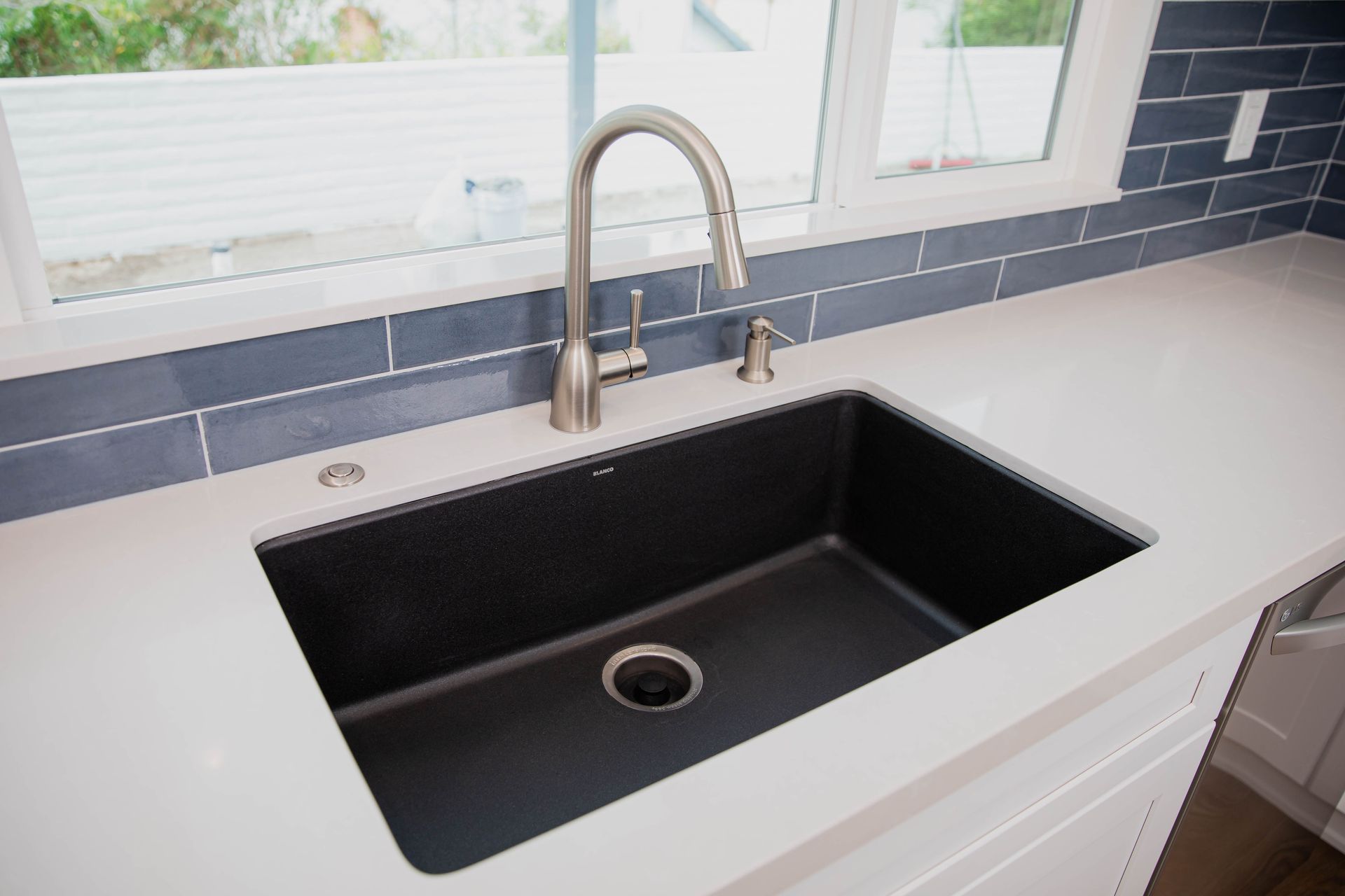 A kitchen sink with a faucet and a window in the background