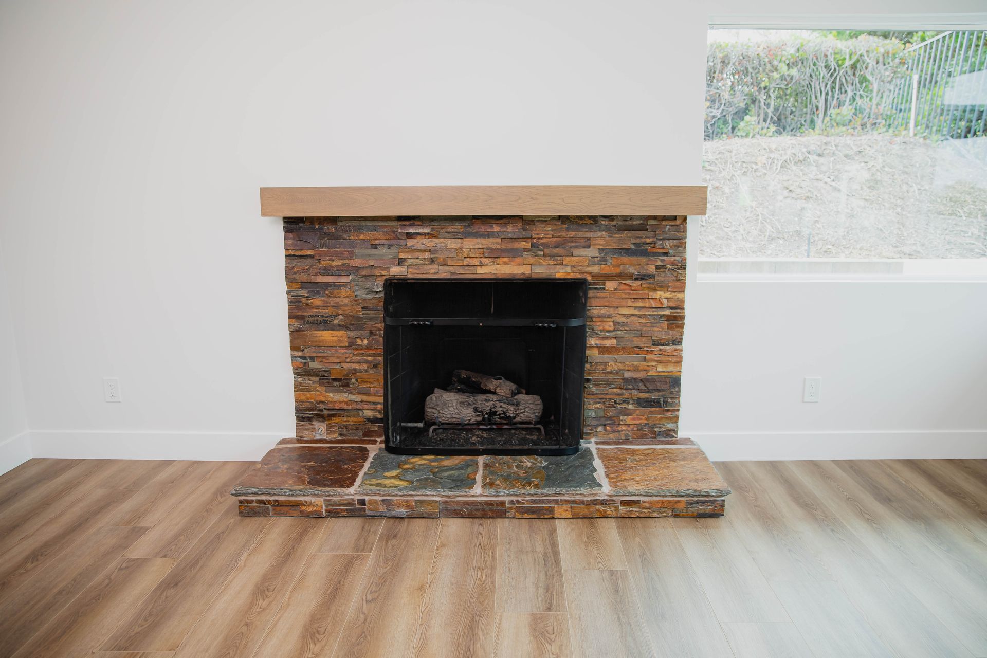 An empty living room with a fireplace and a window.