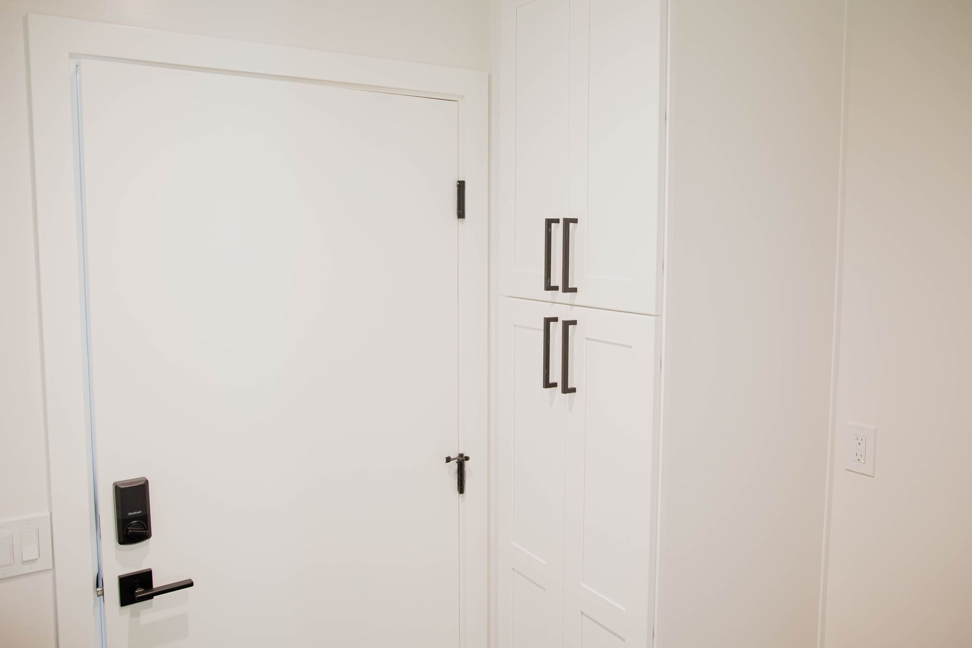 A white door with a black handle is sitting next to a white cabinet.