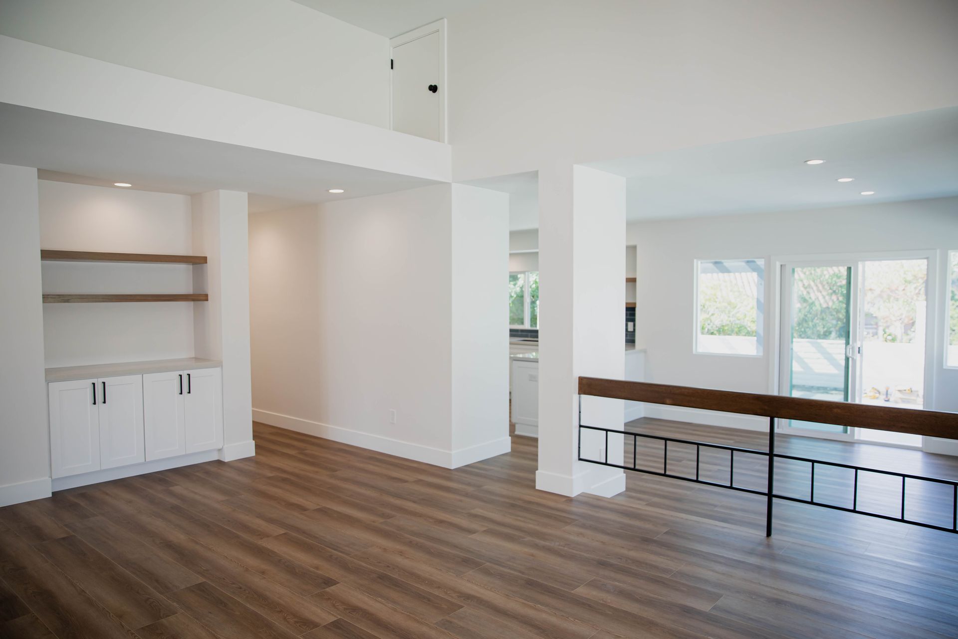 An empty living room with hardwood floors and white walls.