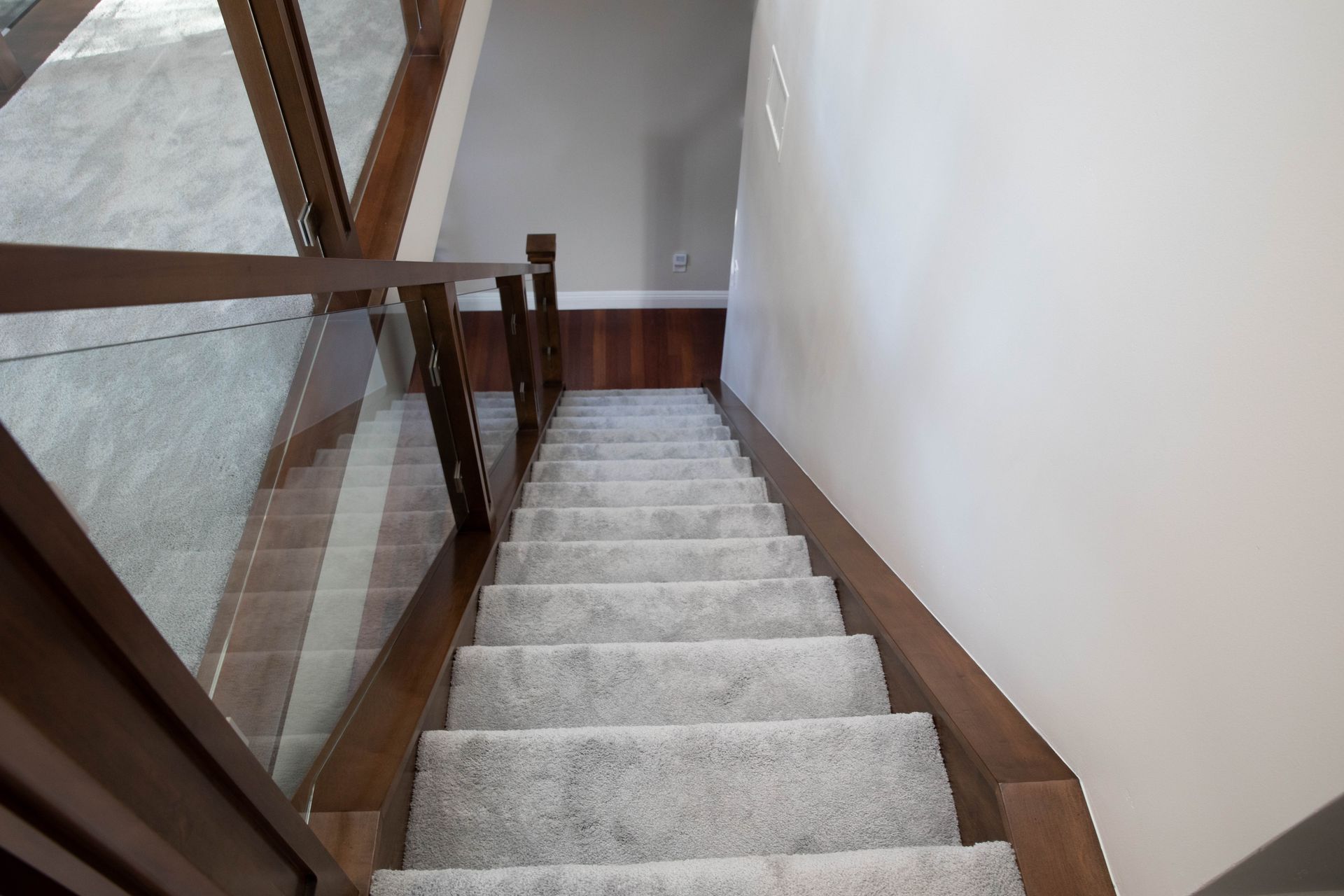 A staircase with carpeted steps and a glass railing