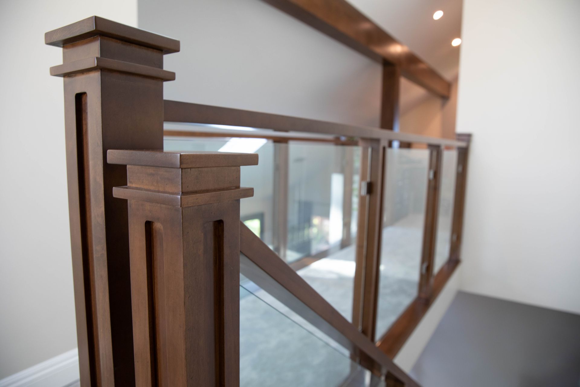 A staircase with a wooden railing and a glass railing