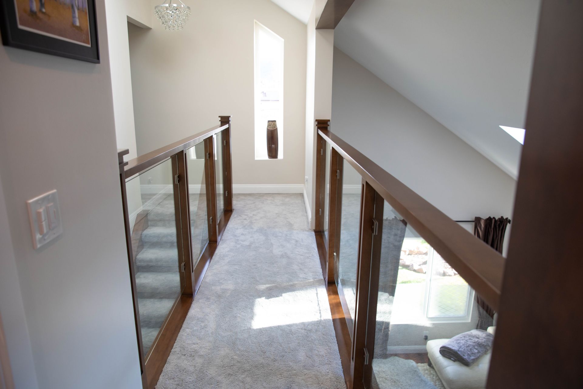 A hallway in a house with stairs and a glass railing