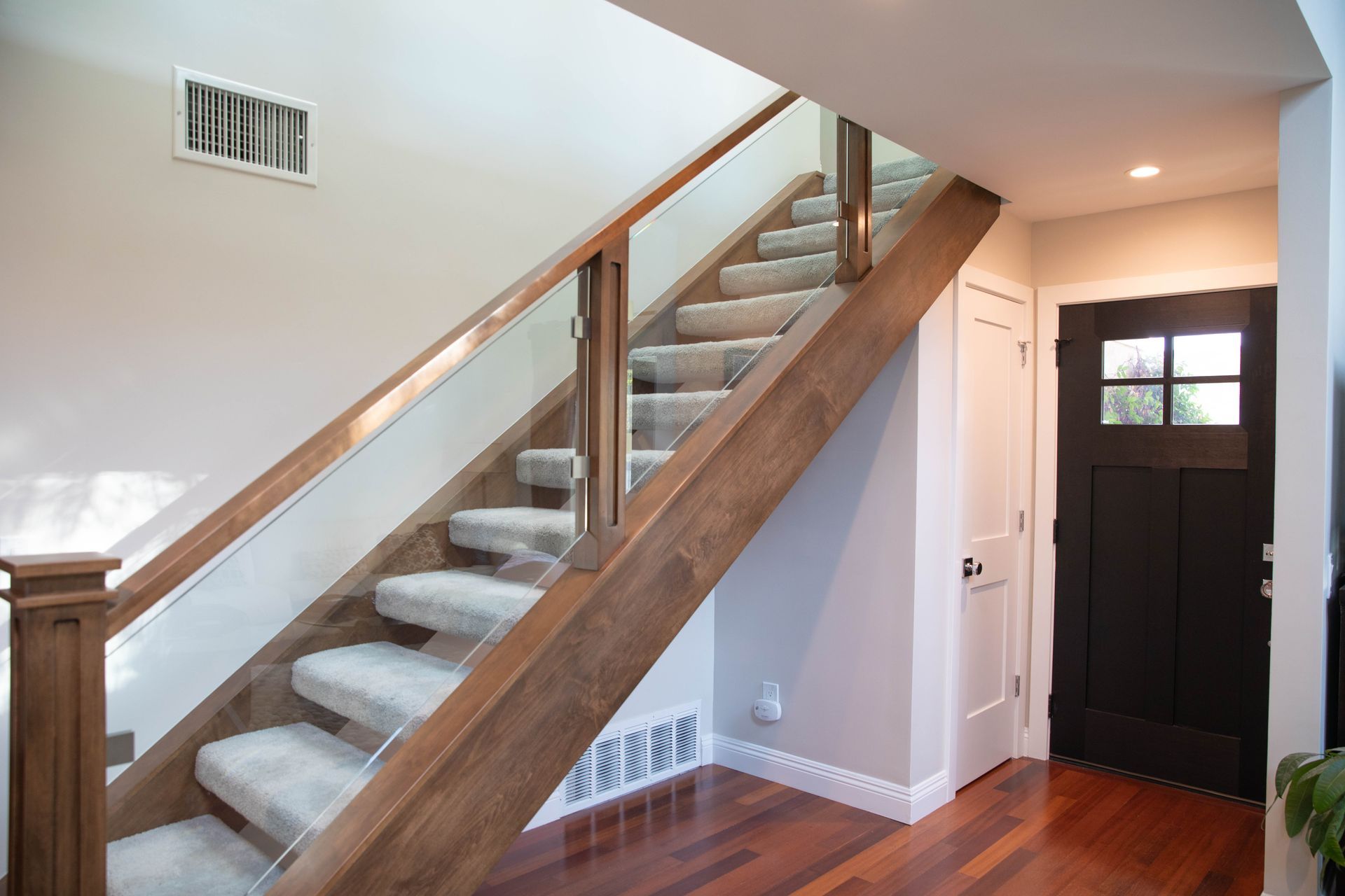A wooden staircase with a glass railing in a hallway