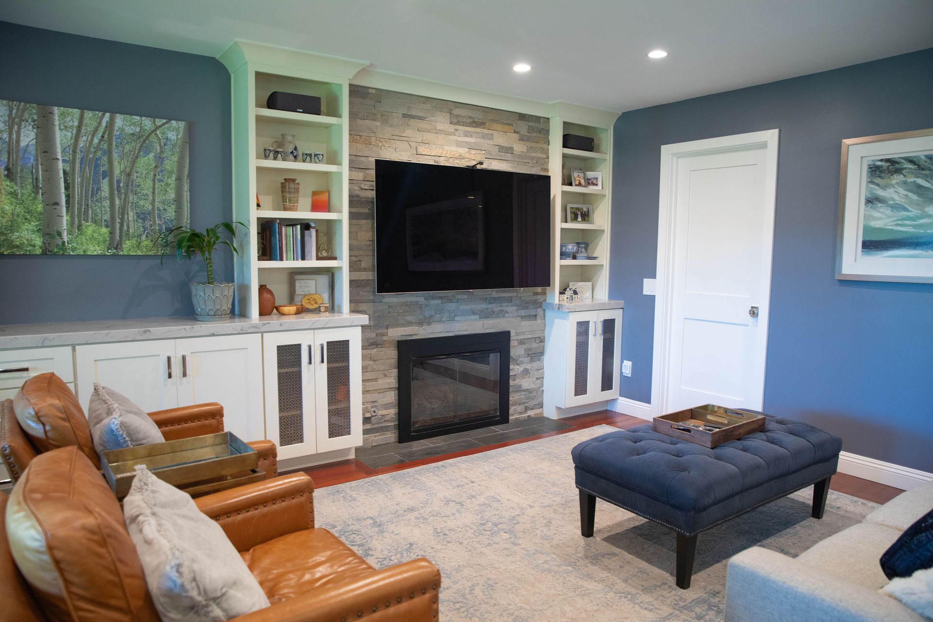 A living room with a fireplace , couch , chairs and a flat screen tv.