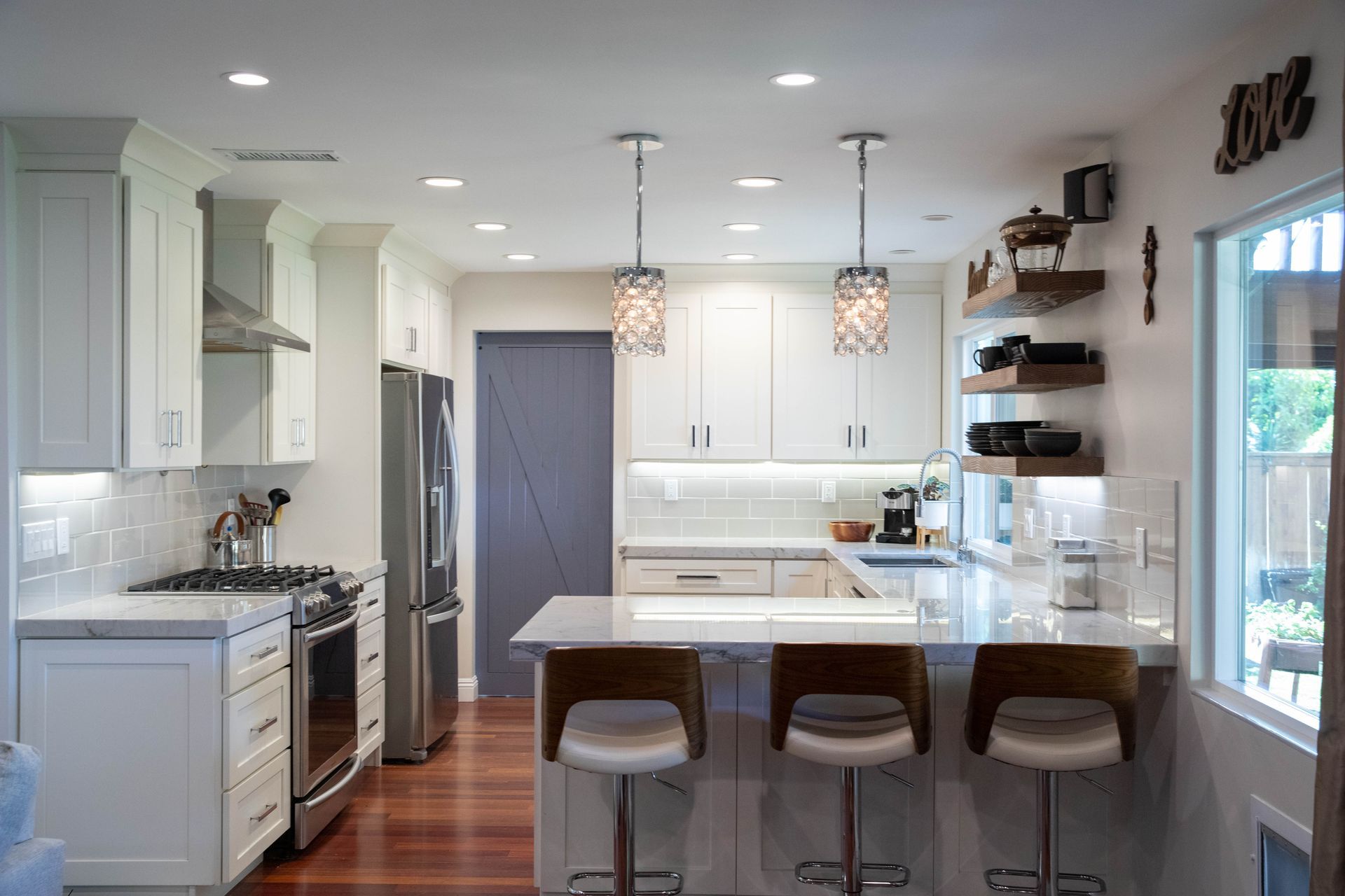 A kitchen with white cabinets , stainless steel appliances , and a large island.
