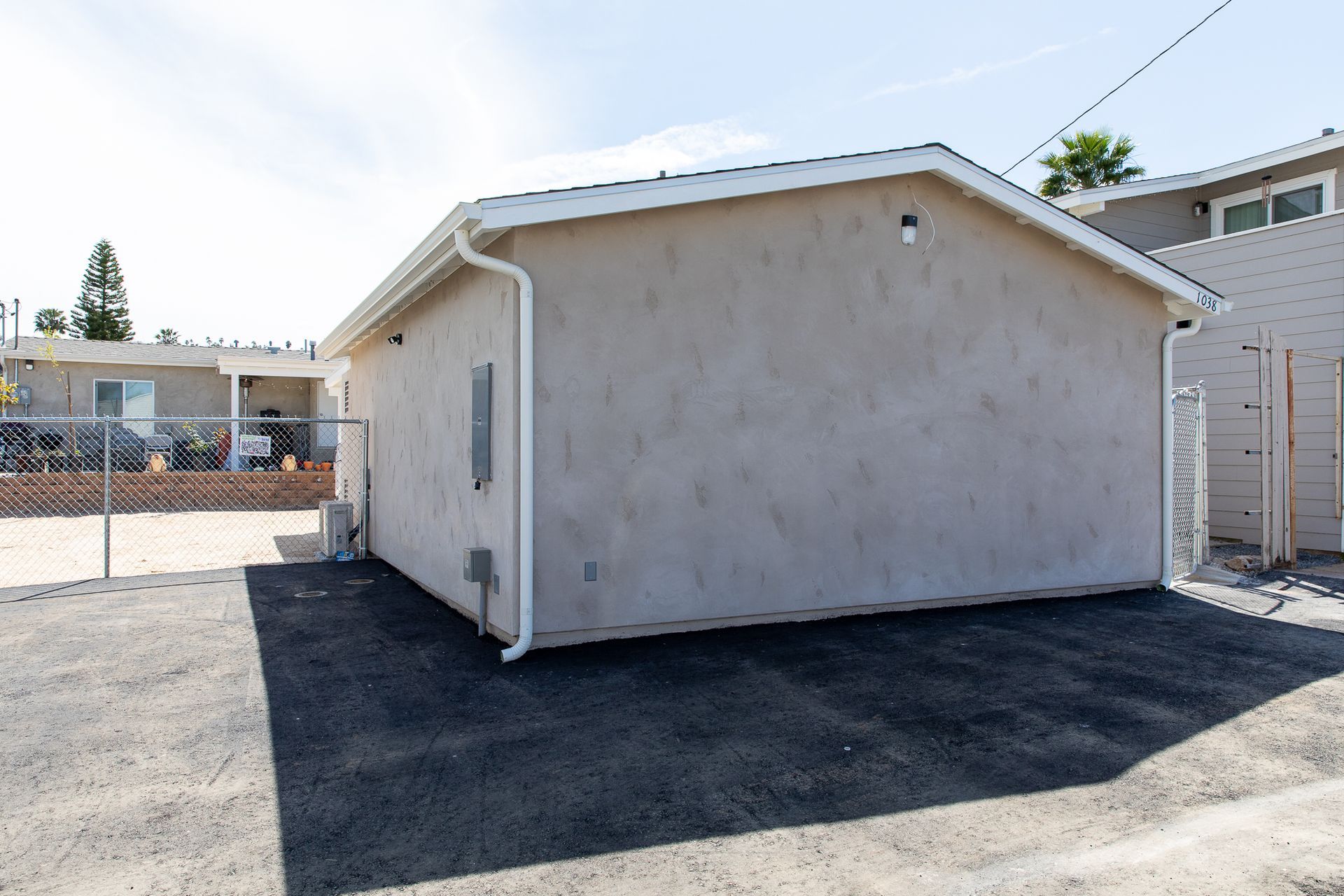 A small building with a white roof is sitting in a dirt lot.