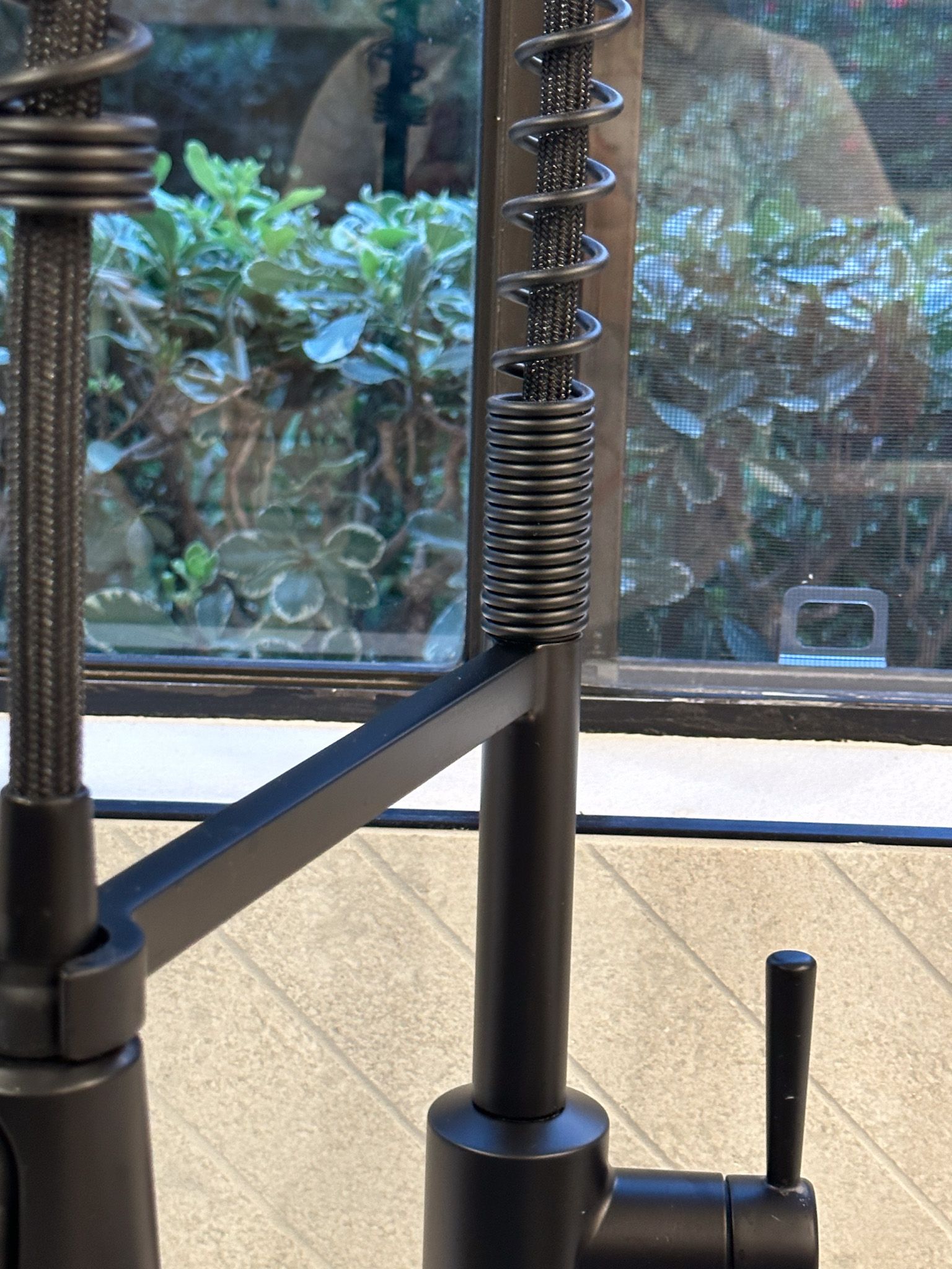 A black faucet is sitting in front of a window