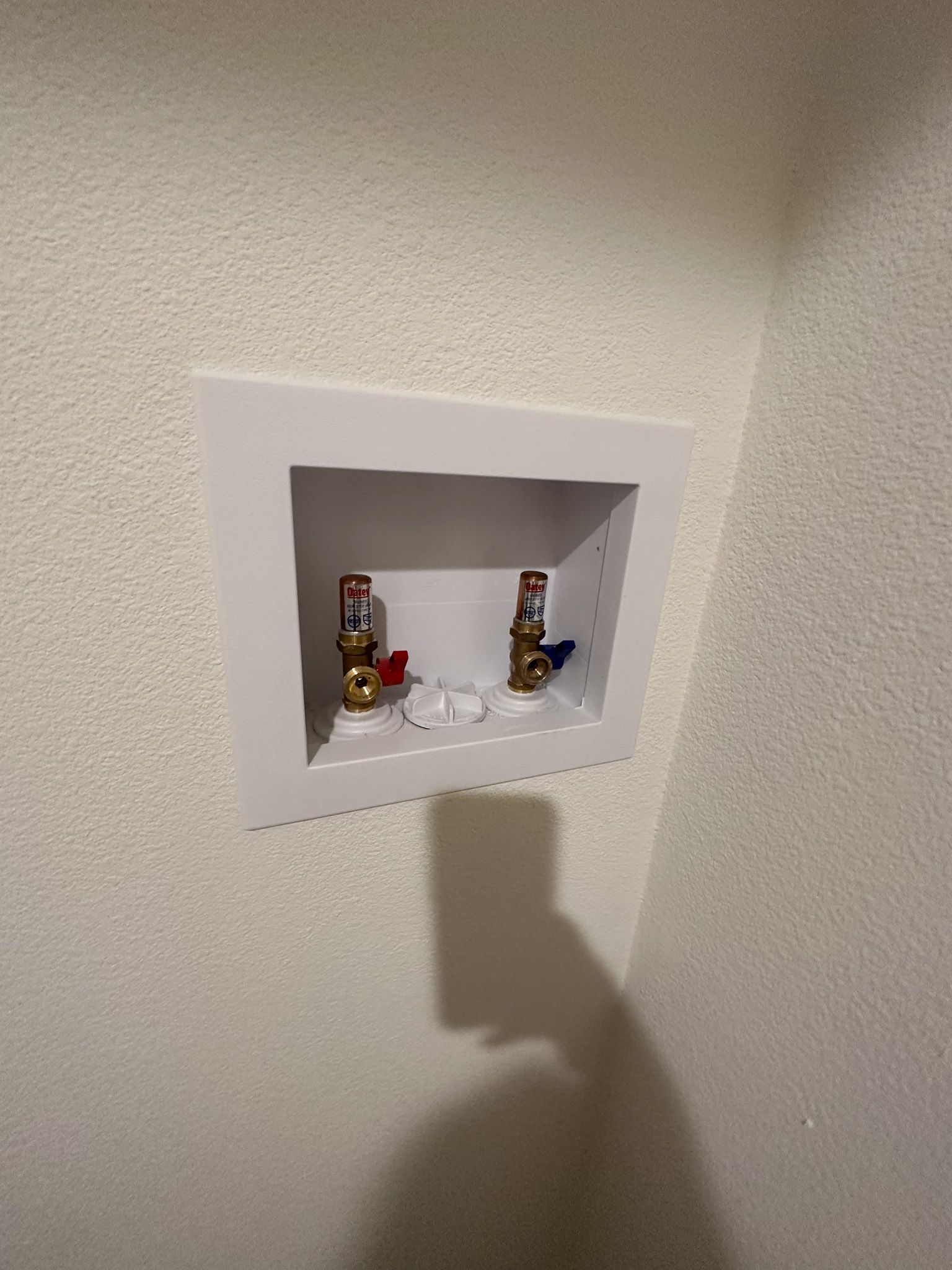 There is a hole in the wall with two valves in it.