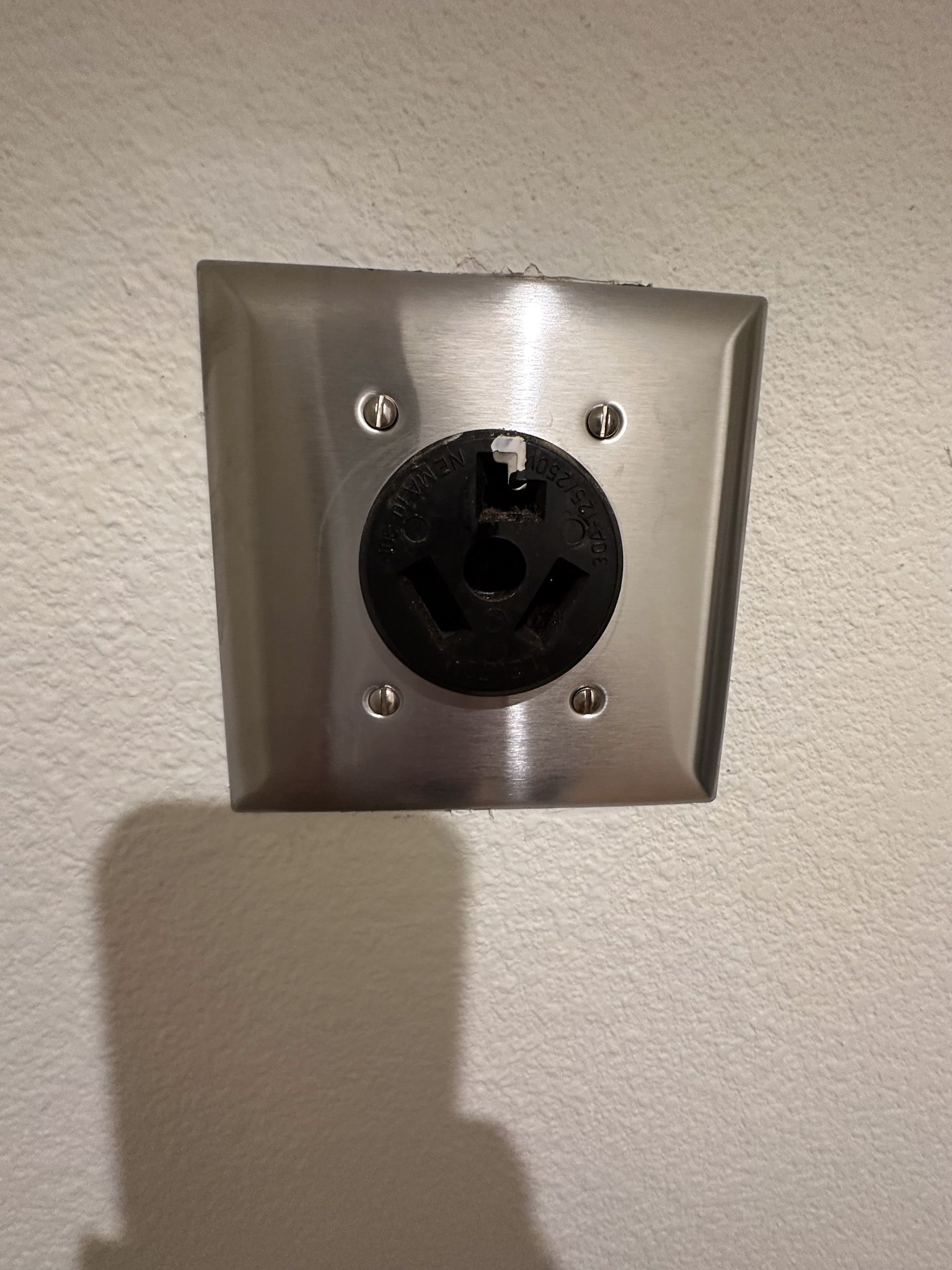 A stainless steel electrical outlet on a white wall.